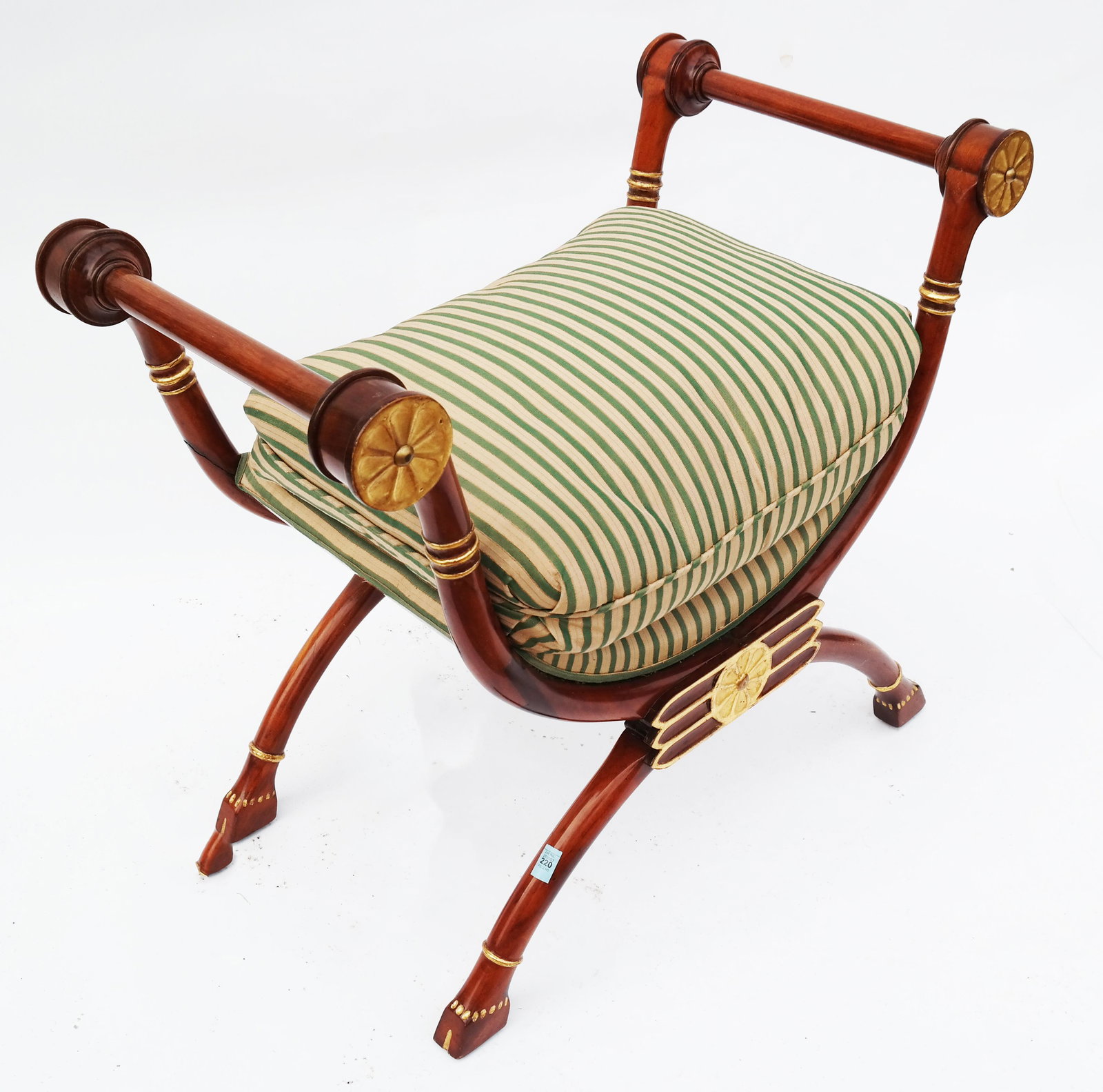 Neoclassical-Style Parcel Gilt Curule Bench: Neoclassical-style pacel gilt curule bench, having rosette motifs at arms and base, on hoof feet, with striped upholstered seat cushions. [26" H x 31" W x 21" D]. In good condition.