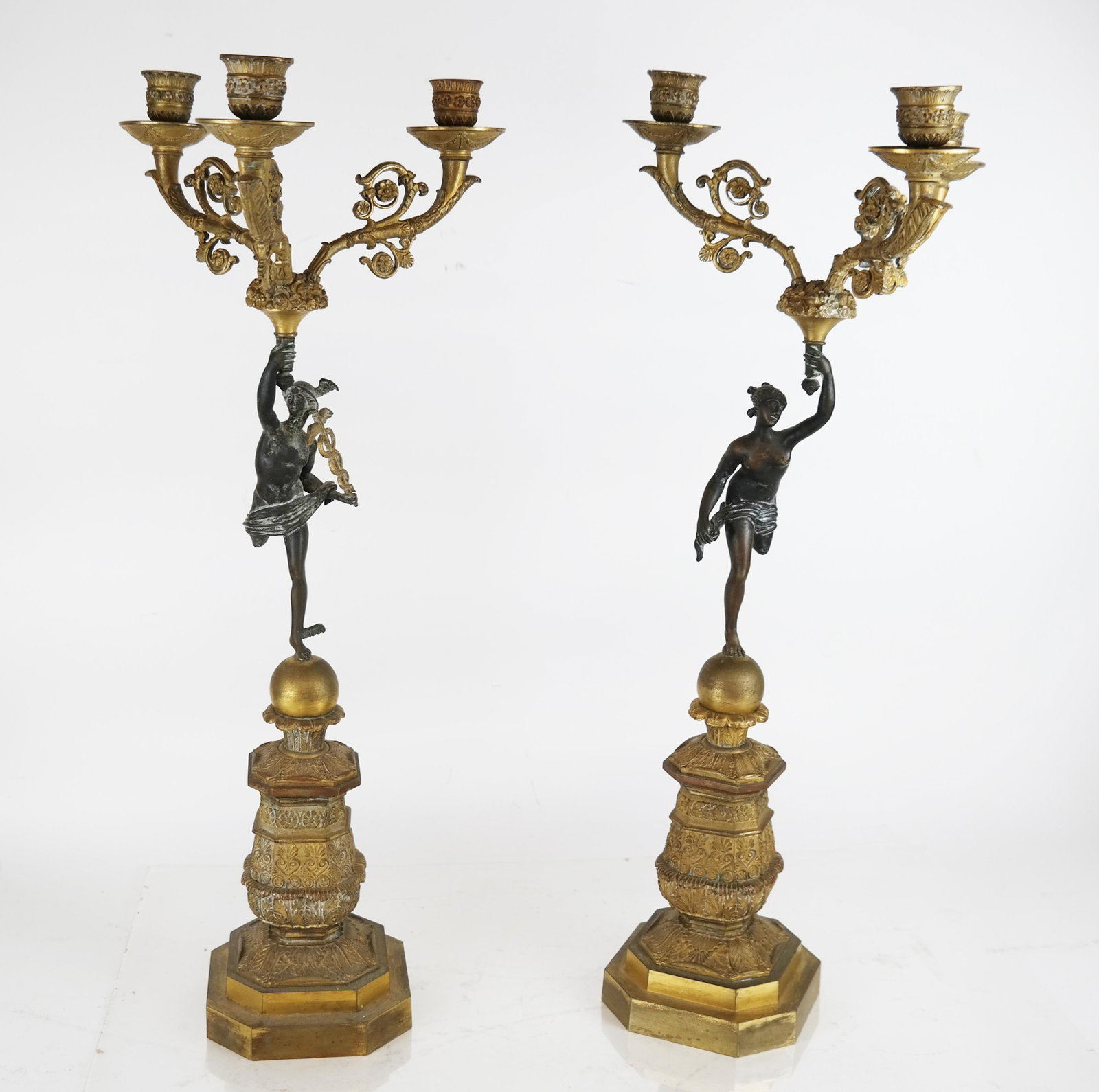 Pair of Gilt Bronze Neoclassical Candelabra: Pair of gilt bronze Neoclassical candelabra, with mythological running figures. [22 1/4" H x 8 1/2" W x 8 1/2" D].