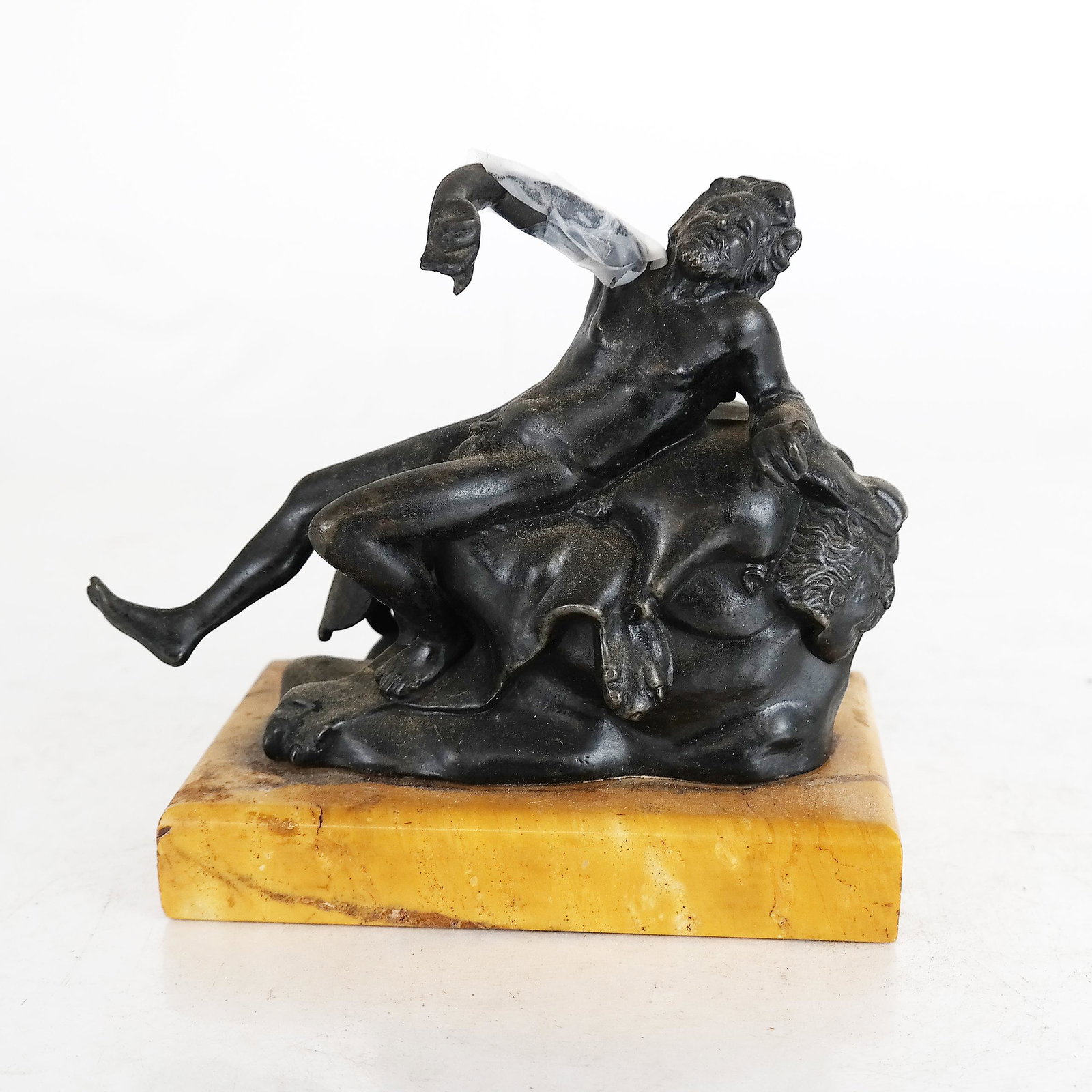 Bronze Reclining Male Figurine: Bronze reclining man figurine, black patinated. [Overall: 5" H x 5 1/2" W x 3 1/4" D]. Lower arm broken off, but present.