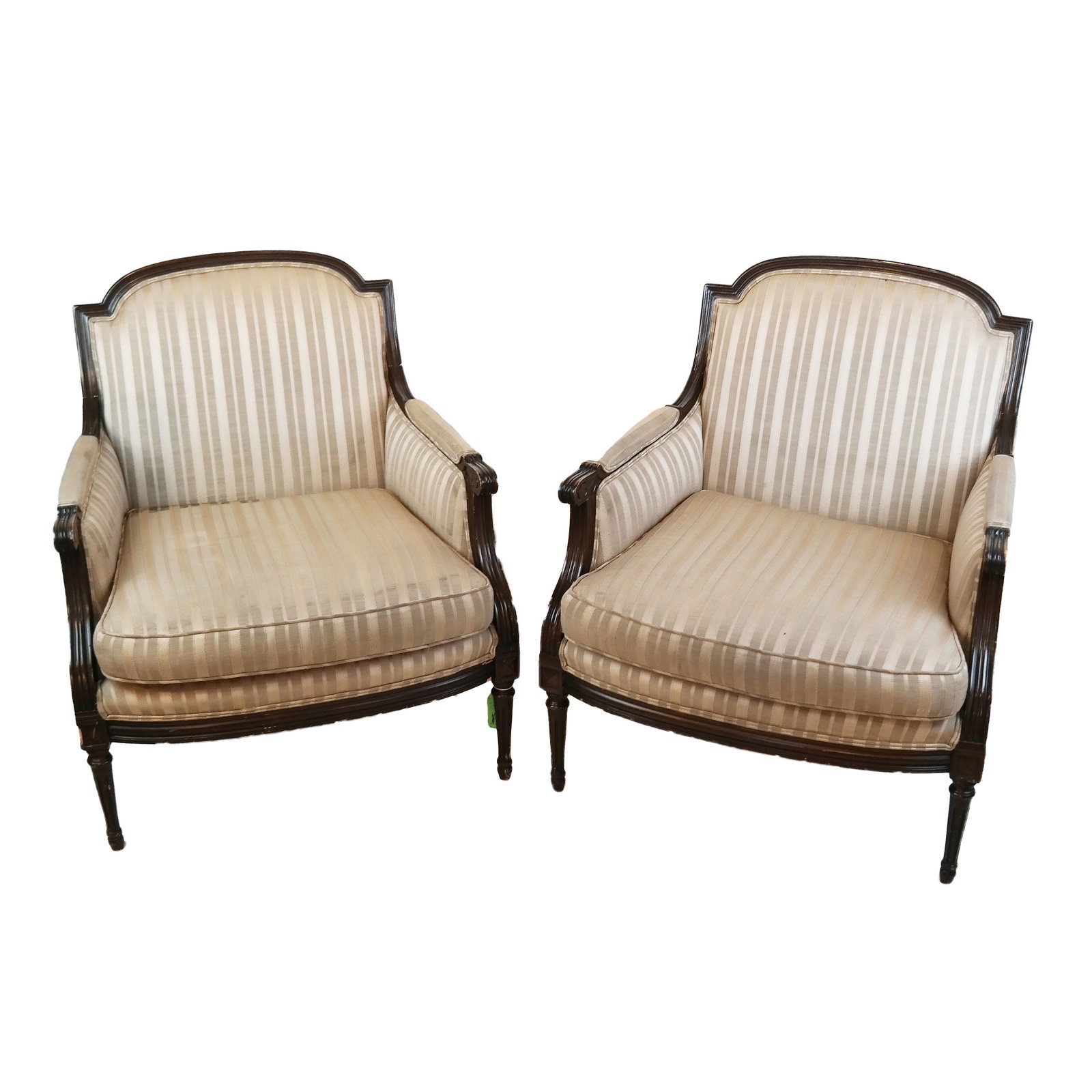 Pair of French Bergeres: Pair of Louis XVI-style bergeres with striped upholstery. [38"H x 31" W x 26" D]. Normal wear as with age to frames; some soiling and staining to the upholstery, with a large stain on one of the insid