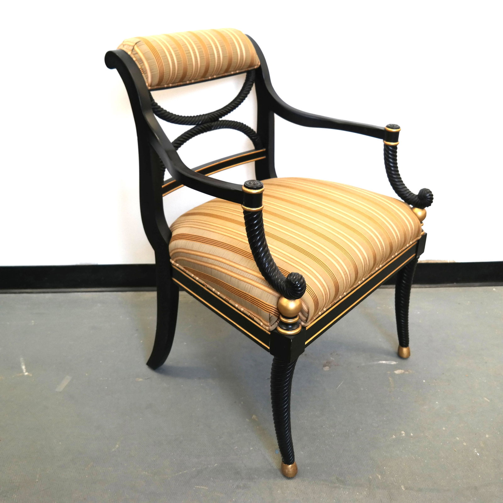 Sheraton-Style Open Arm Chair: Sheraton-style open arm chair, ebonized, with carved twist "X" back, arms and front legs. Upholstered backrest and seat; gilt trim. [35" H x 26" W x 28" D].