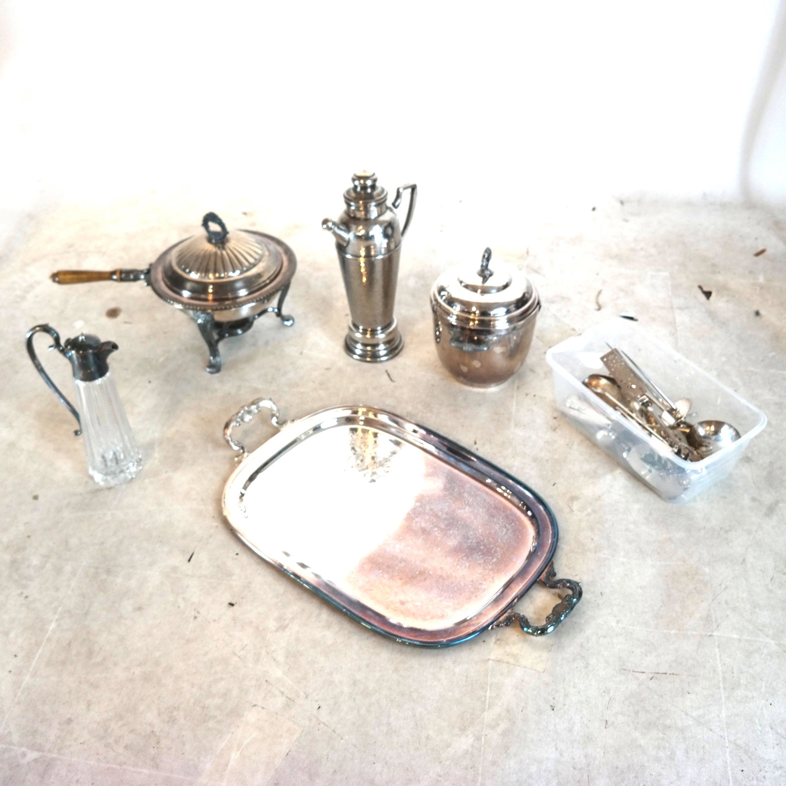 Lot of Silver Plate Flatware, Others: Lot includes a carafe, wine bucket (with large cracks), food warming pan on stand, and more. [Tray: 25" L x 15" W].