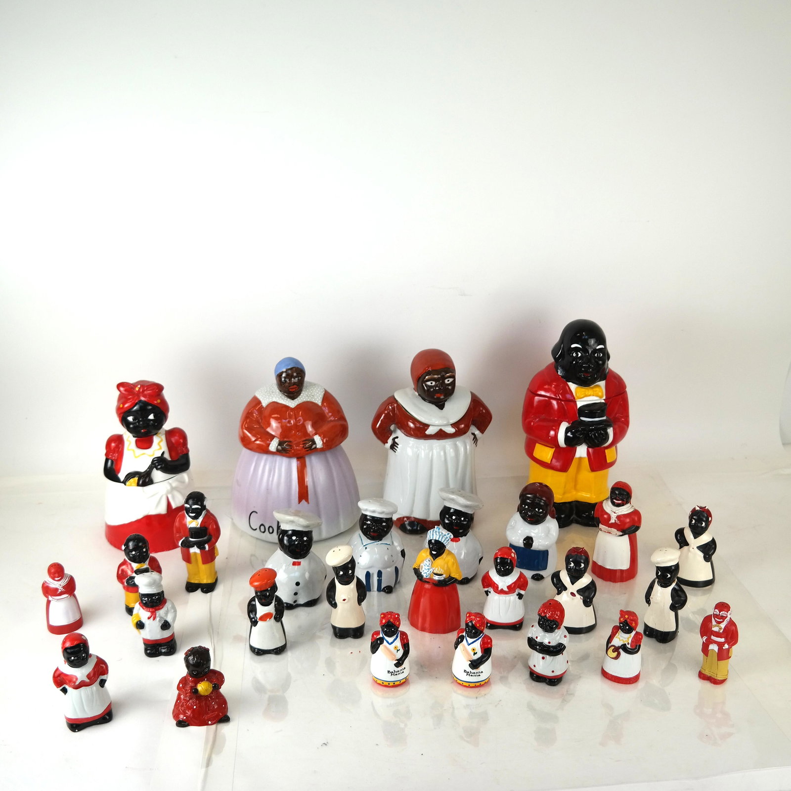 26+ "Mammy" and -Style Kitchen Articles: Lot includes cookie jars, shakers, and others, in porcelain and plastic. [Tallest: 12" H]. In good condition.