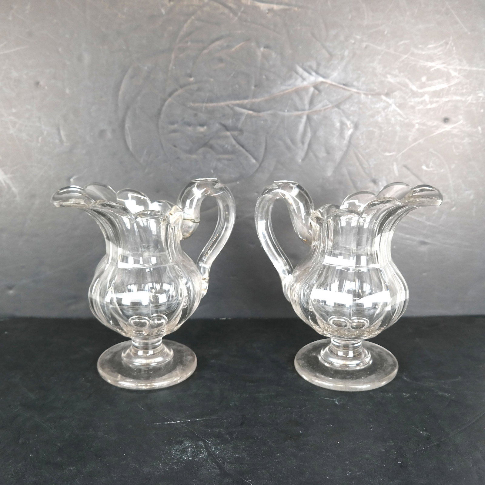 Pair of American Fruit Glass Small Pitchers: Pair of 19th century fine glass pitchers. One handle with old stapled repair.