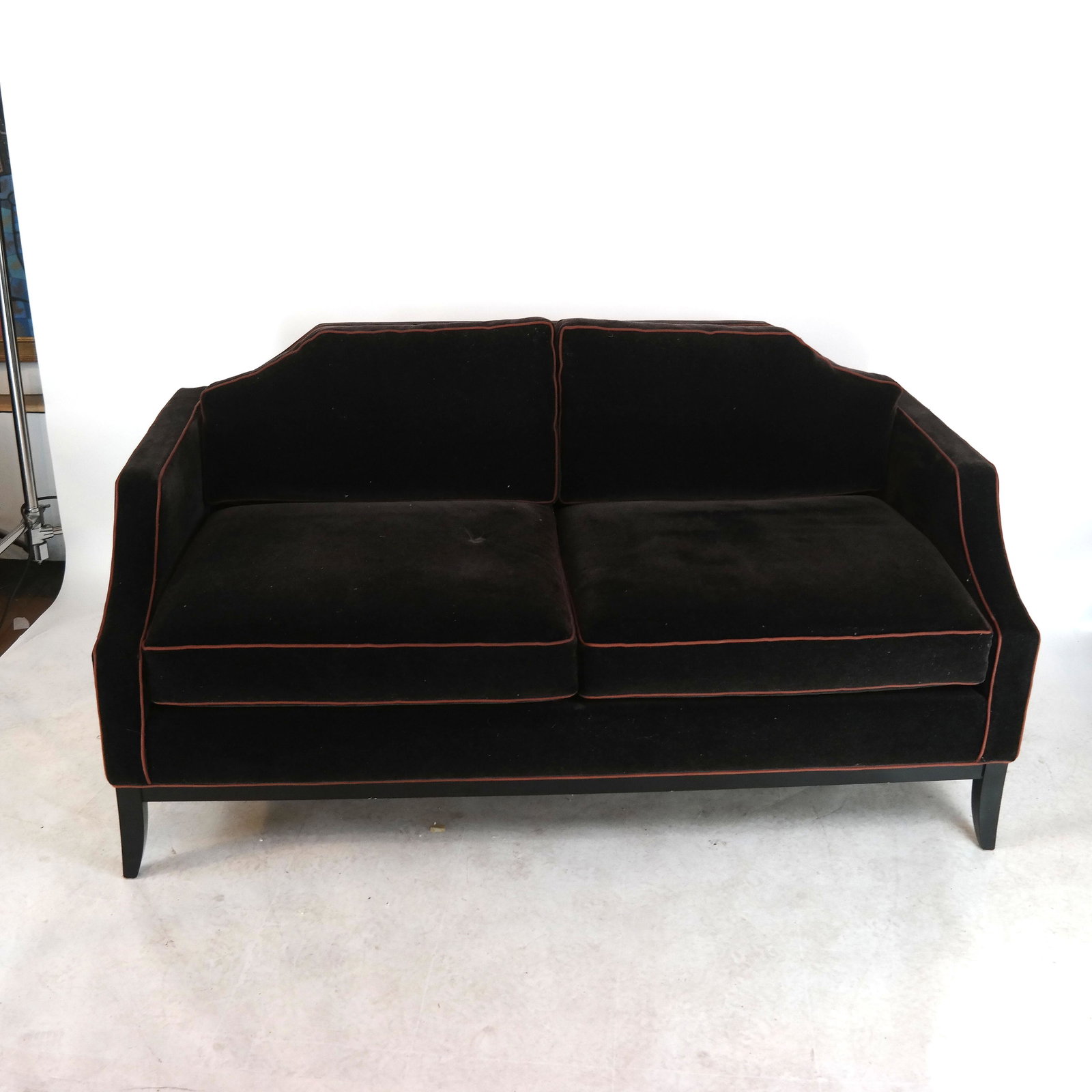Modern Black Velour Upholstered Settee: Modern black velour upholstered settee / sofa, with brown piping. [32" H x 64 1/2" W x 35 1/2" D]. In good condition.
