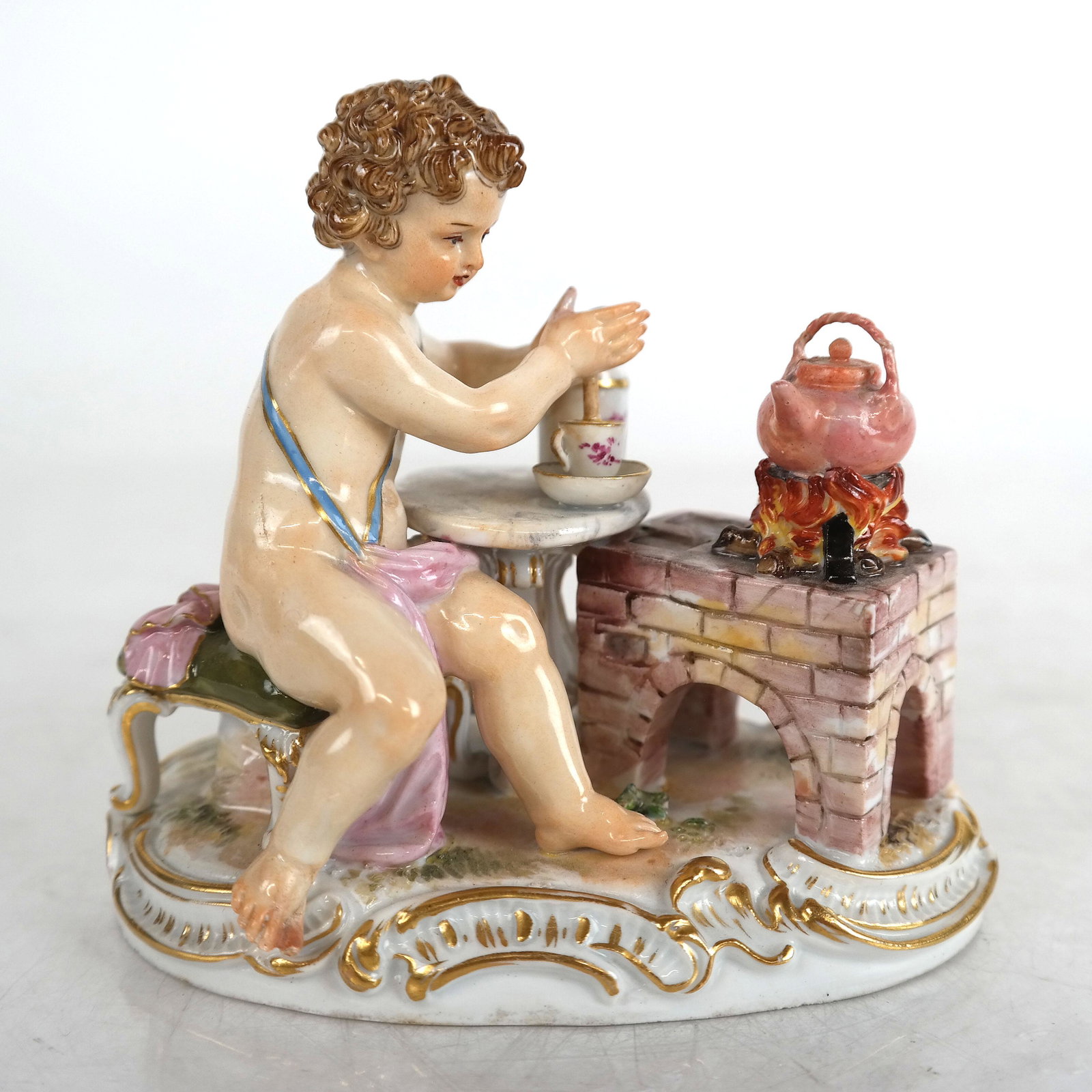 Meissen Sculpture of Cherub at Table: Meissen porcelain sculpture of a cherub at a table. [3 1/2" H x 4 1/2" W x 2 1/2" D]. In good condition.