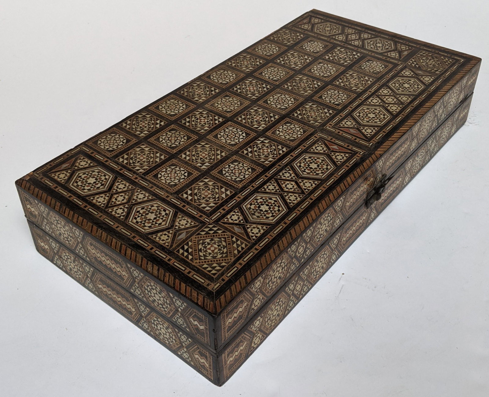 Moroccan Intarsia Backgammon Game Box: Geometric inlaid wood, mother-of-pearl and bone backgammon game box with richly decorated interior and exterior. [3" H x 15 3/4" W x 8" D]. Some wear, otherwise in good condition.