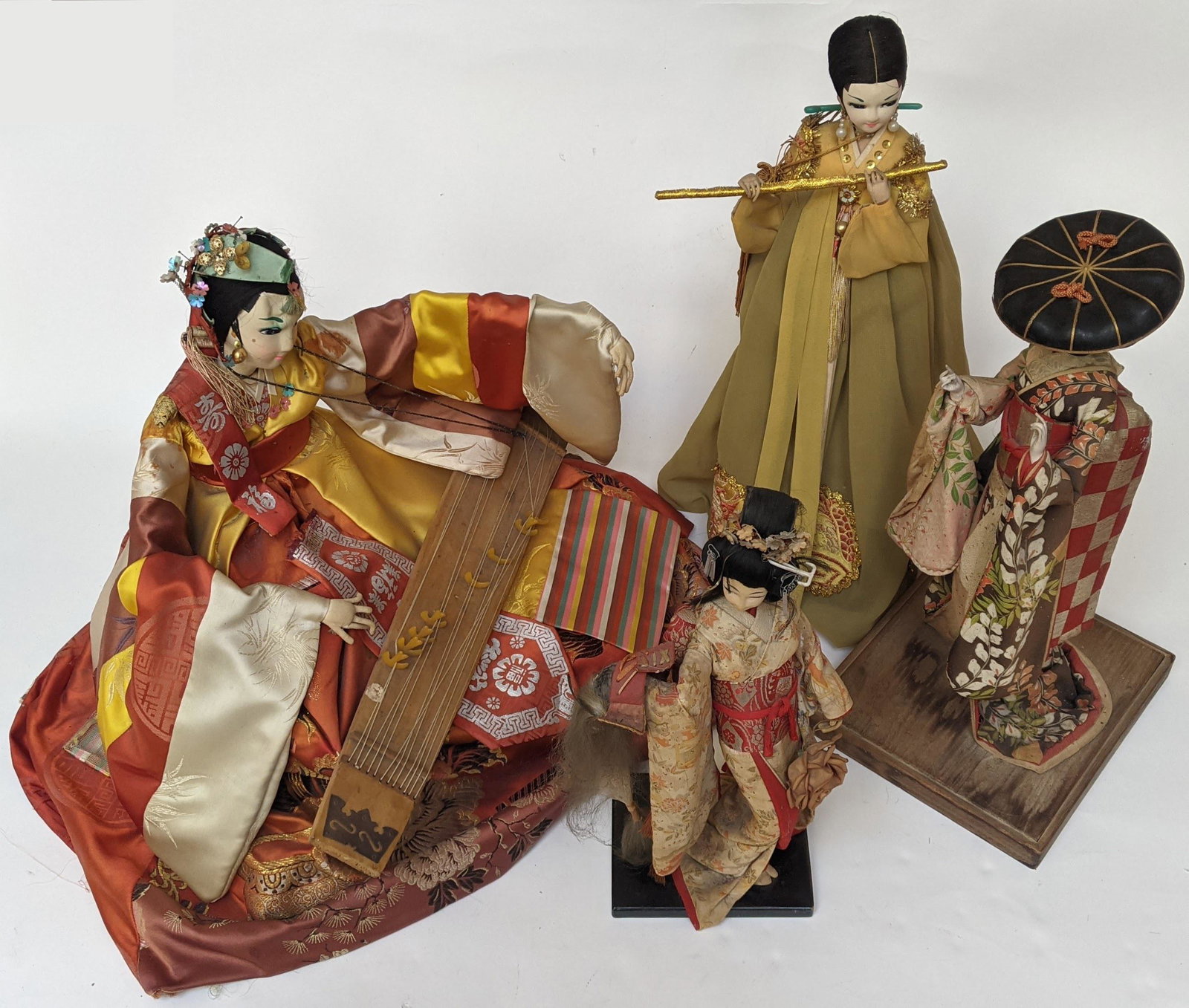 Lot of Four Korean Dolls: Four Korean dolls playing instruments, circa 1950. [Largest: 15" H; Smallest: 13" H]. In good condition.