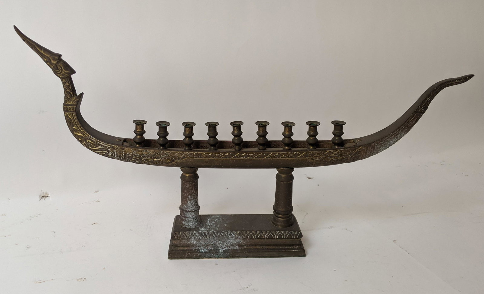 9-Light Brass Menorah Boat: Brass 9-light menorah, shaped as a boat, on raised pilasters. [16" H x 30" W x 4" D]. In good condition.