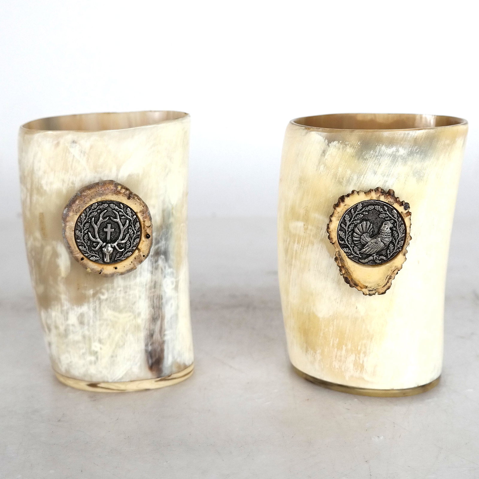 Two Horn Beakers: Two beakers made from horn, with applied bone and metal medallions. [4 3/4" H x 3" W x 2 1/2" D]. In good condition.