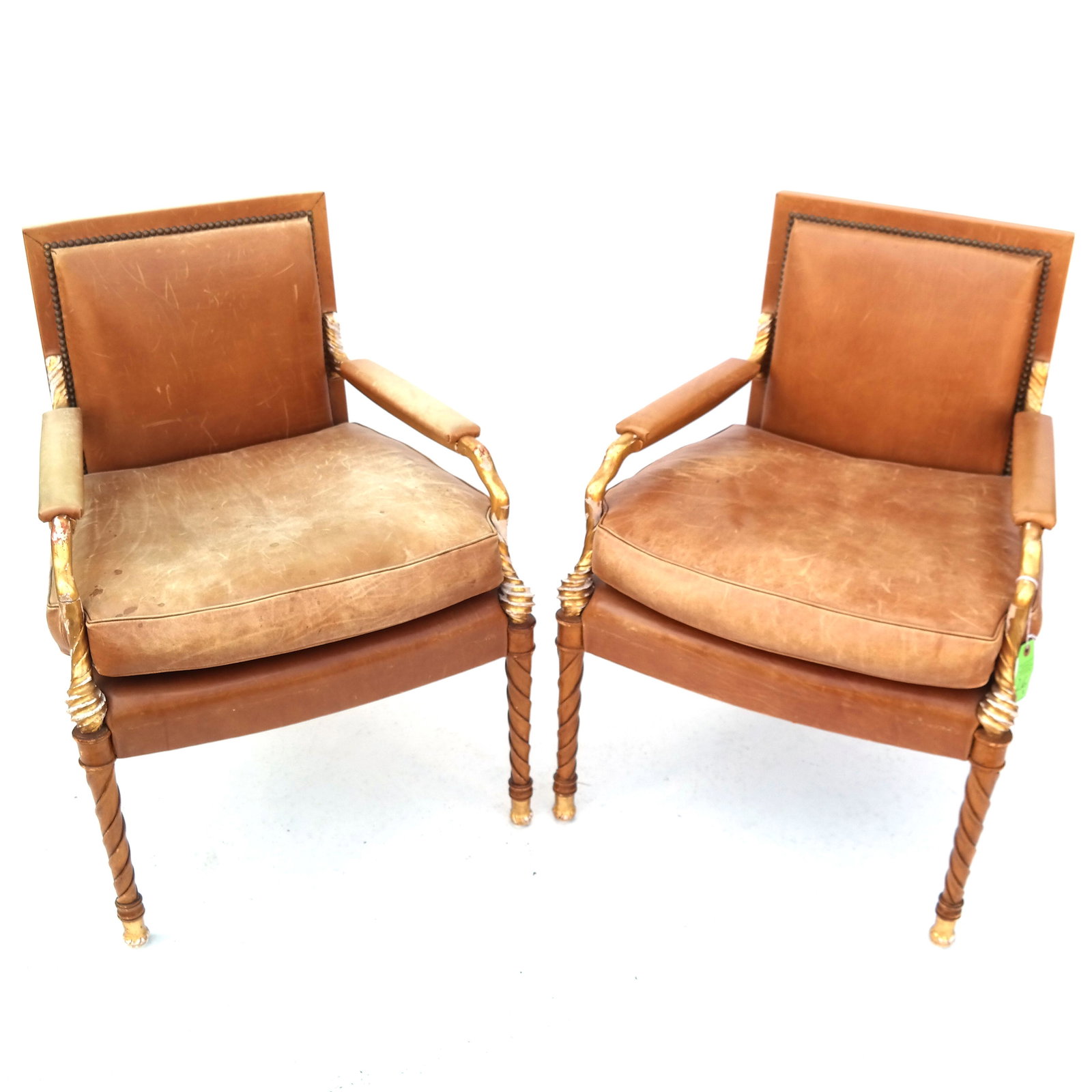 Pair of Neoclassic Parcel Gilt Birch Wood Arm Chairs: Pair of 20th century painted, carved and parcel gilt birch wood arm chairs with leather upholstery. [32 3/4" H x 24 1/2" W x 22 1/2" D]. Structurally sound; heavy gold losses, flaking and chipping. Le