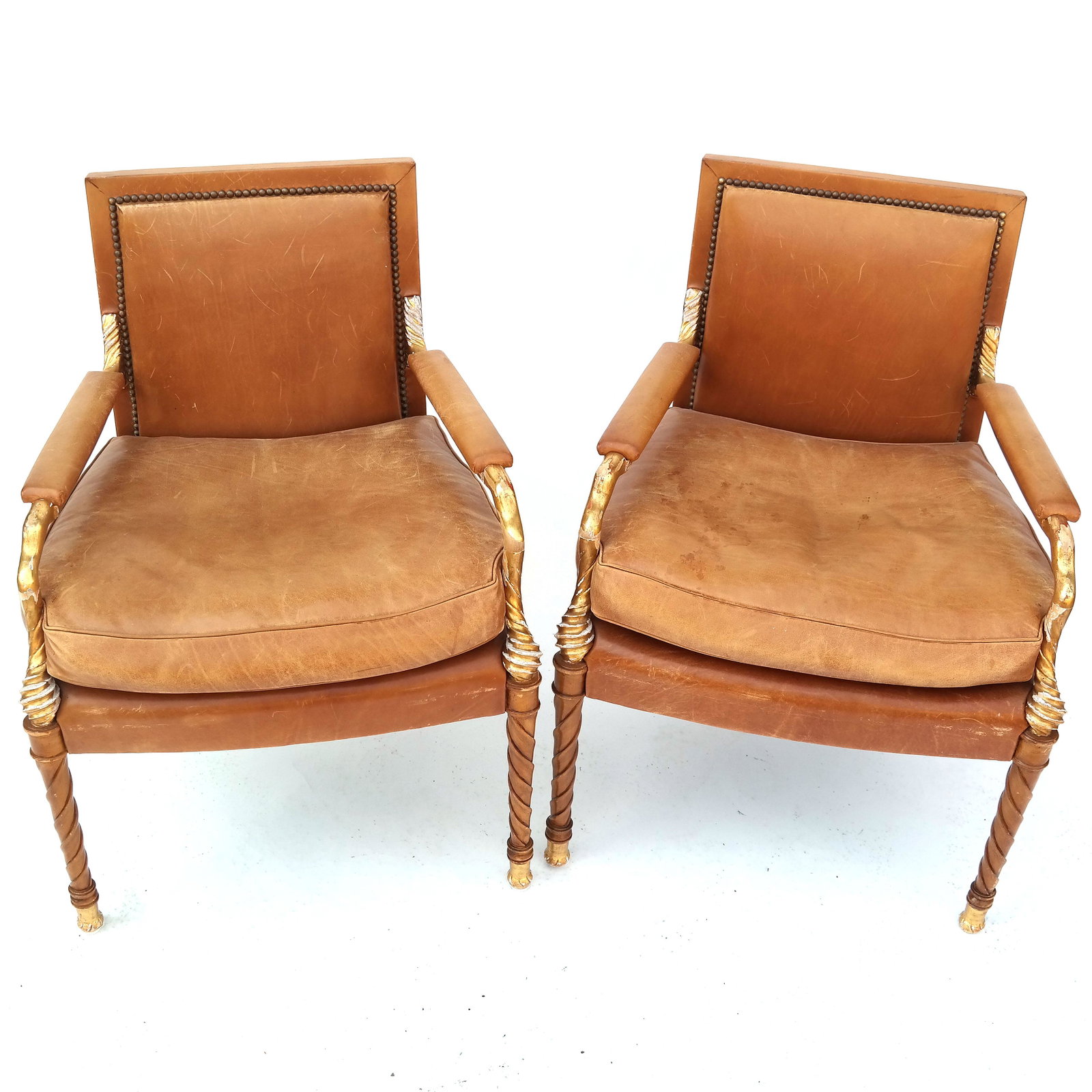 Pair of Neoclassic Parcel Gilt Birch Wood Arm Chairs: Pair of 20th century painted, carved and parcel gilt birch wood arm chairs with leather upholstery. [32 3/4" H x 24 1/2" W x 22 1/2" D]. Structurally sound; heavy gold losses, flaking and chipping. Le