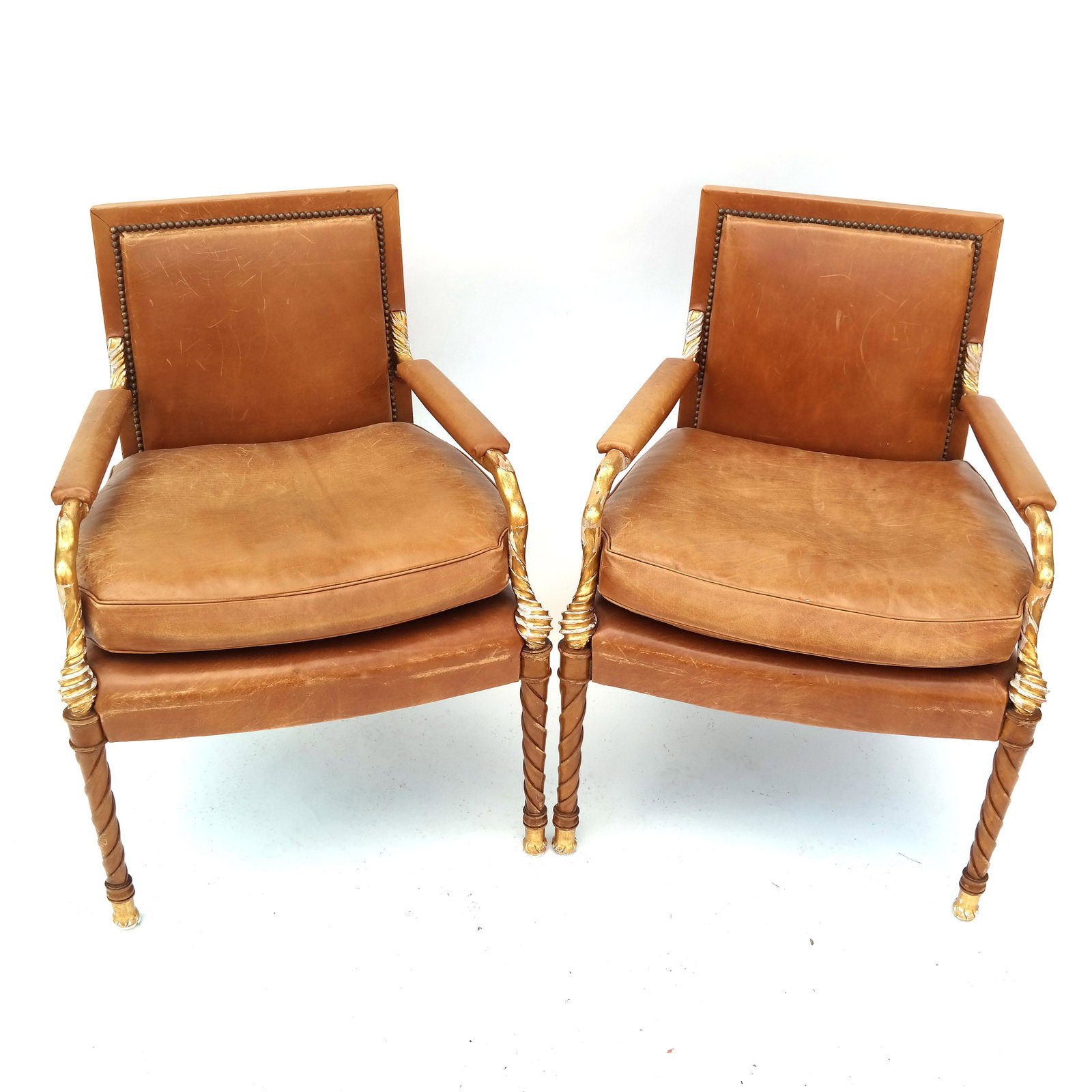 Pair of Neoclassic Parcel Gilt Birch Wood Arm Chairs: Pair of 20th century Neoclassic parcel gilt birch wood arm chairs with leather upholstery. [32 3/4" H x 24 1/2" W x 22 1/2" D]. Structurally sound; heavy gold losses, flaking and chipping. Leather is 