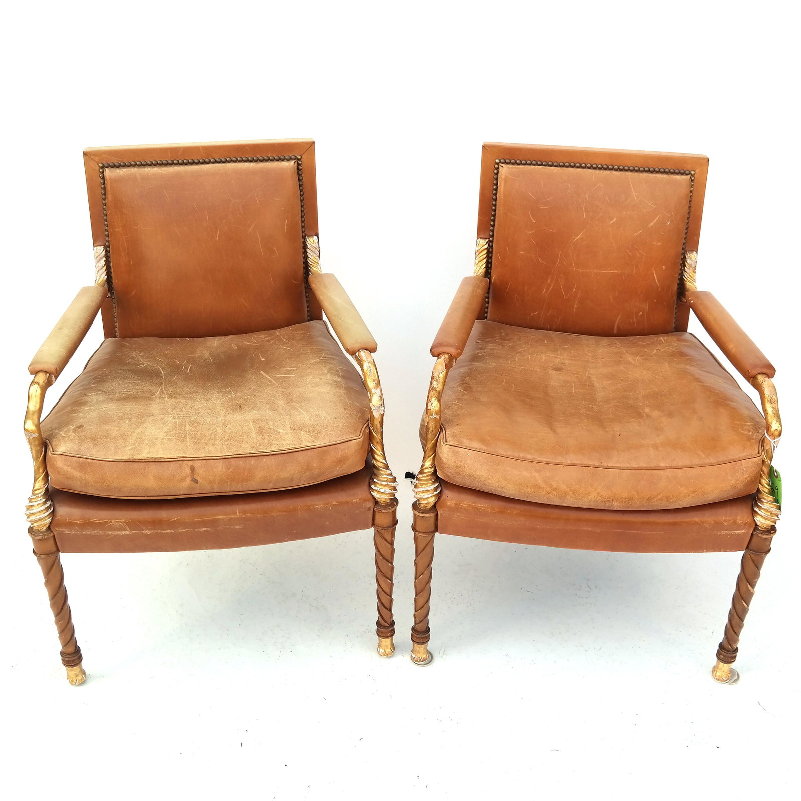 Pair of Neoclassic Parcel Gilt Birch Wood Arm Chairs: Pair of 20th century Neoclassic parcel gilt birch wood arm chairs with leather upholstery. [32 3/4" H x 24 1/2" W x 22 1/2" D]. Structurally sound; heavy gold losses, flaking and chipping. Leather is 