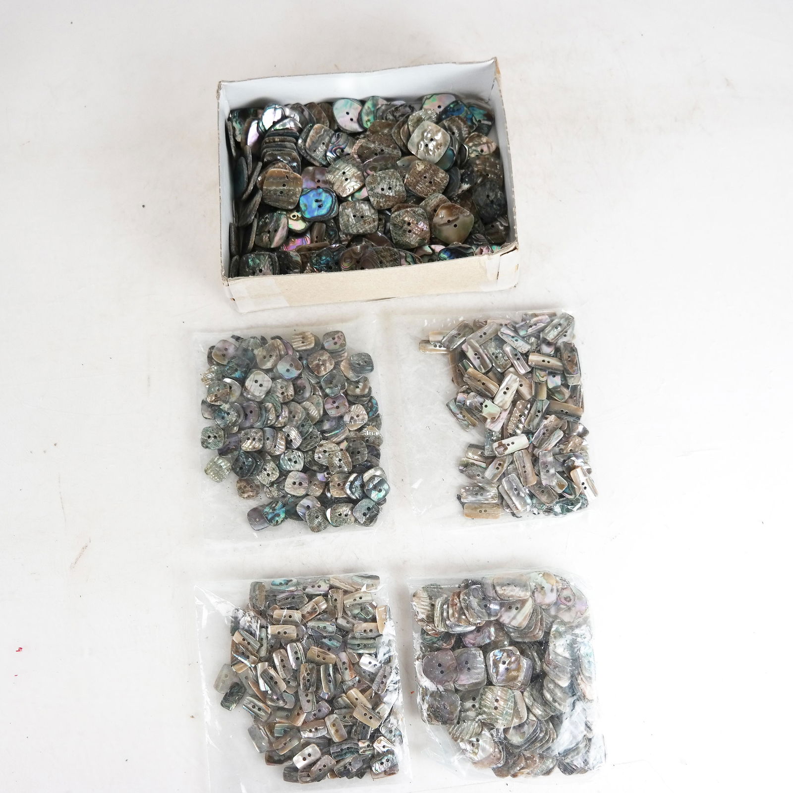 Box of Abalone Shell Buttons: Uncounted lot of abalone shell buttons, mostly 1" square, with others 5/16" square and a 1" rectangle.