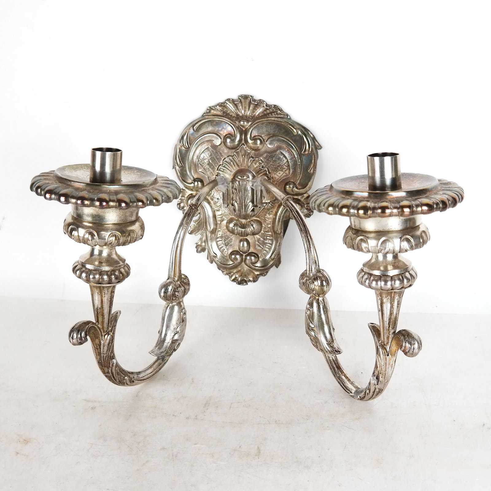 Belgian Silver 2-Arm Sconce: Belgian silver sconce with cartouche backplate in repousse with two insert scrolling arms. 17th century, with modern fittings. [10" H].