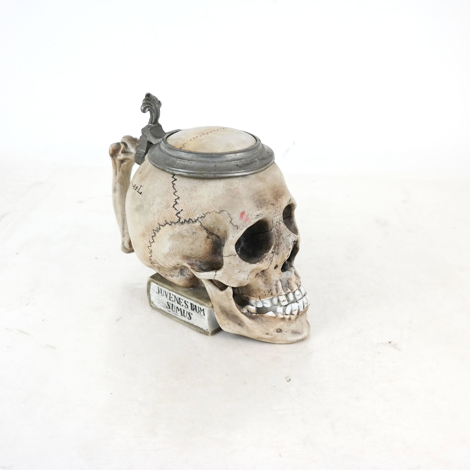 English Porcelain Faux Skull Stein: English porcelain stein with faux skull on book with Latin writing, with pewter mounted cover. [7" H x 5" W x 8" D].