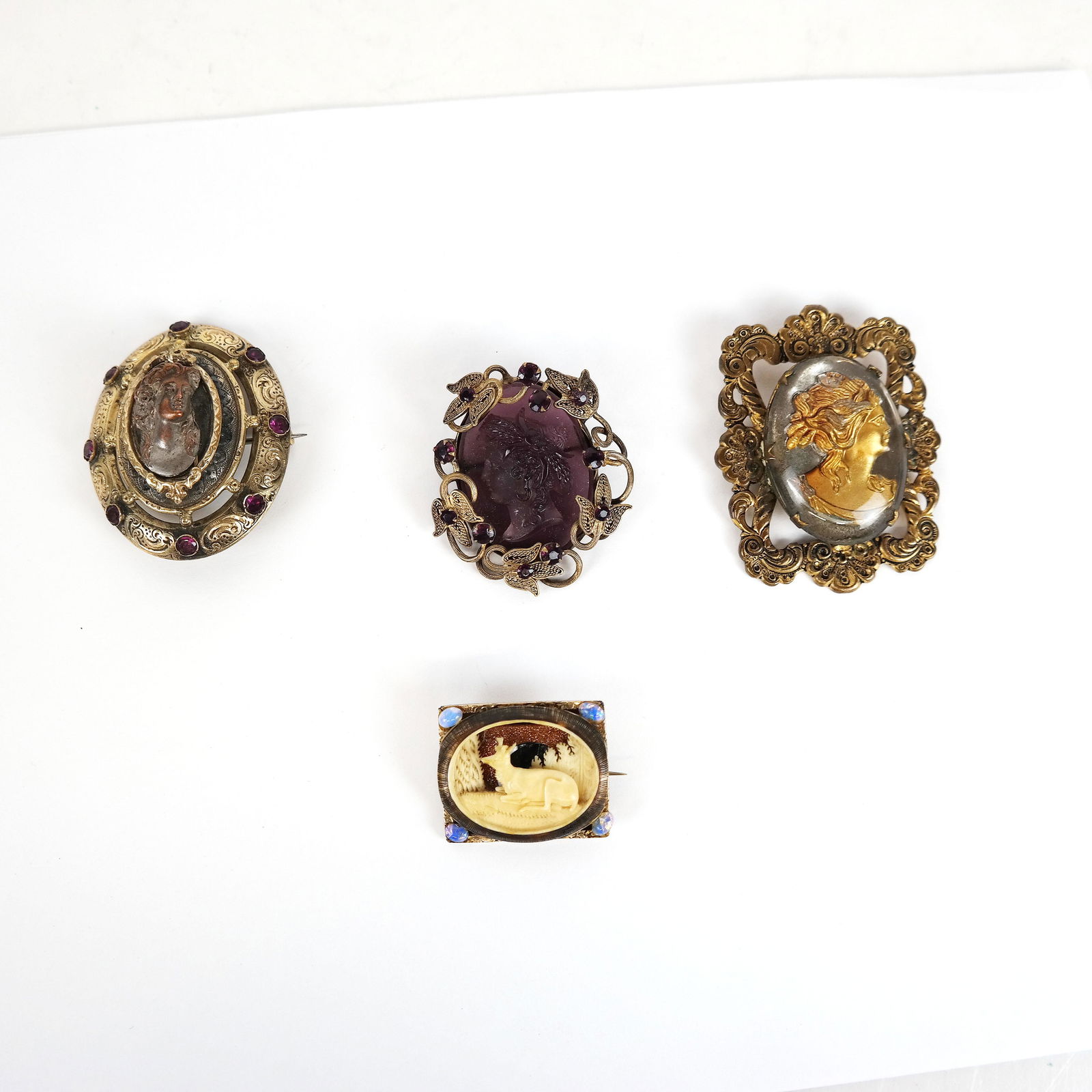 Lot of Four Vintage Cameo & Portrait Pins: Lot of vintage / antique brooches, some with carved glass, carved bone and cast copper portraits, in jeweled gold-tone filigree frames. [Largest: 2 1/2" H x 1 7/8" W]. In good condition.