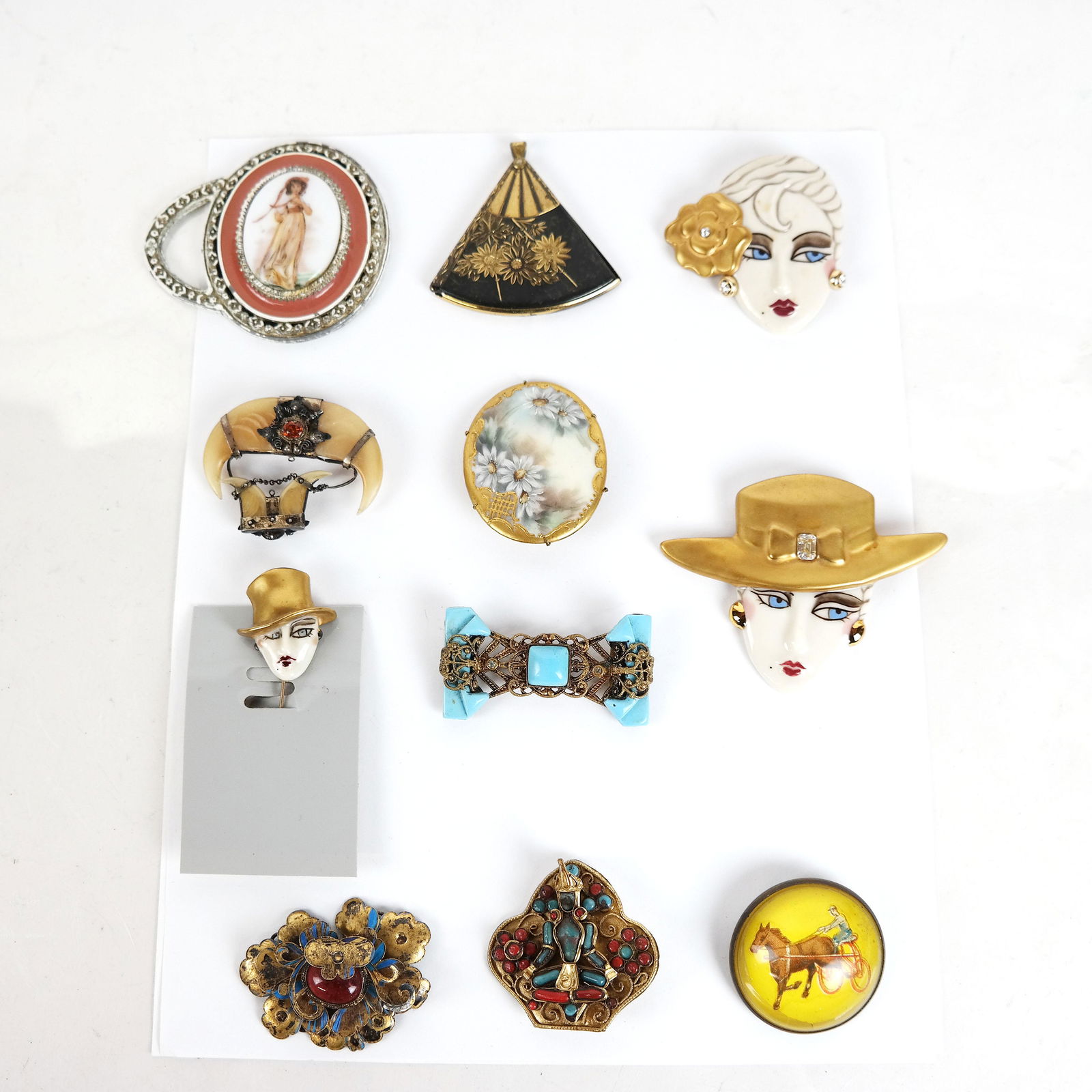 Lot of Vintage Brooches, Pins, Others (11): Lot of vintage / antique brooches, including signed Chinese, a pendant and three pins of "flappers", signed "HE", together with a painted portrait pocket mirror and a horn crescent pendant. [Largest (