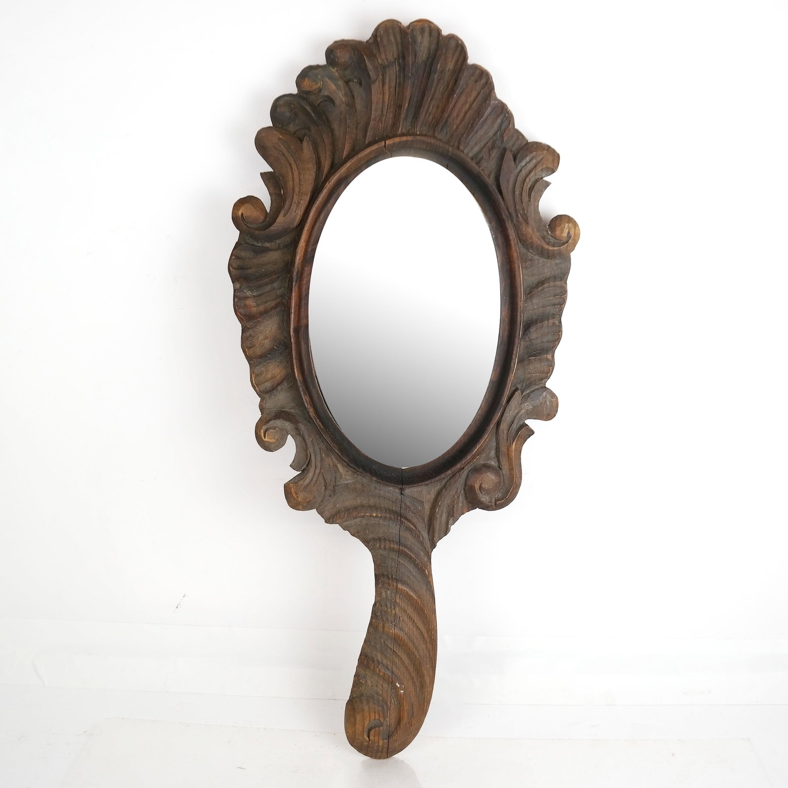 Hand-Carved Wood Hand Mirror: Hand-carved hand mirror with oval glass. [25 1/2" H x 12" W]. Splits to wood.