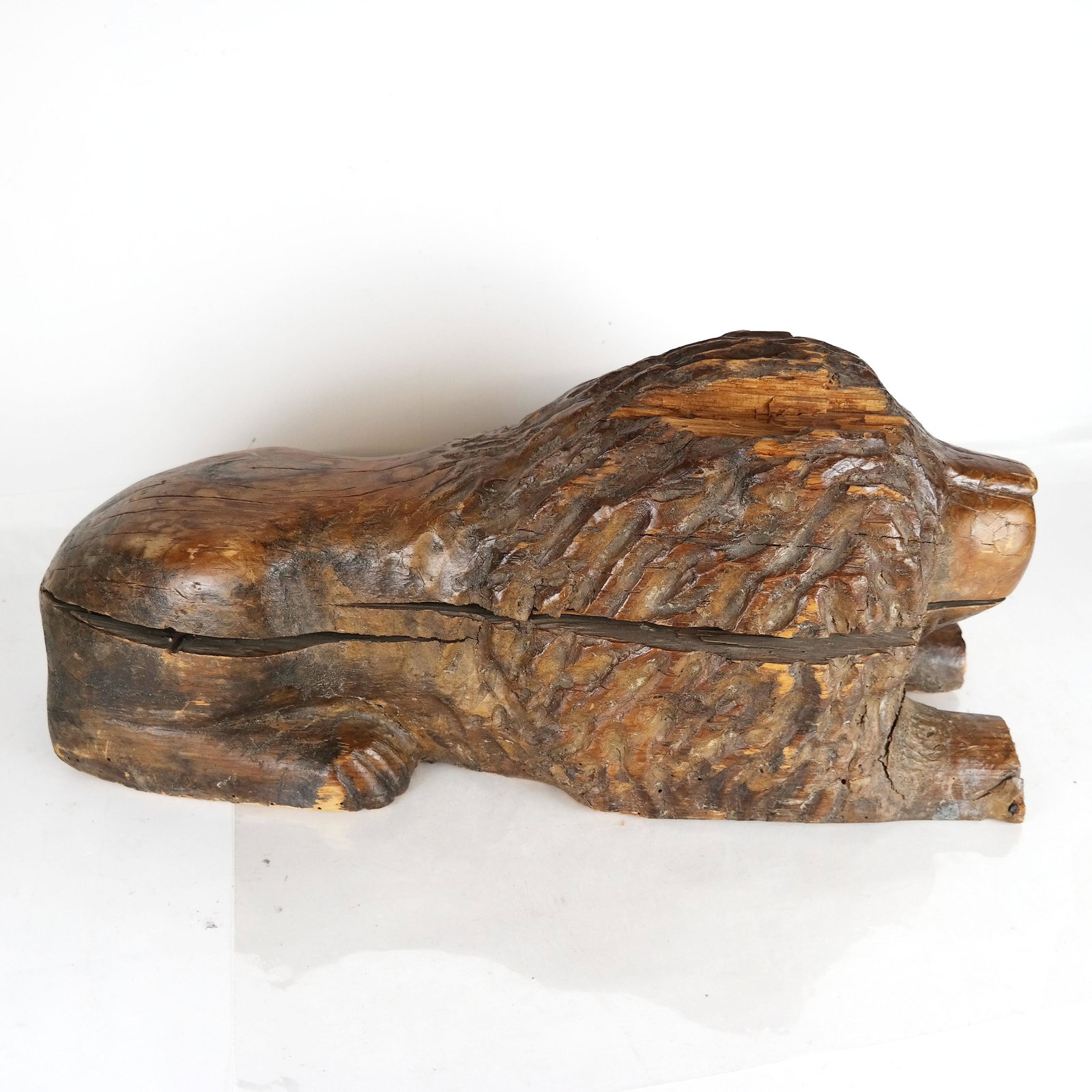 Carved Wood Sentry Lion: Folk Art-style carved wood lion in sentry pose. Provenance: From the Upper East Side estate of a prominent NYC interior decorator. [11" H x 10" W x 26" D]. Splits; losses; wear.