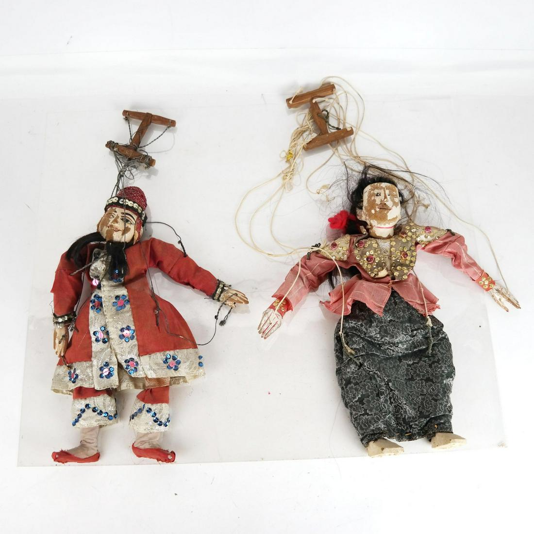 Two Painted and Carved Marionettes: Two painted and carved marionettes in Thai silk garments.