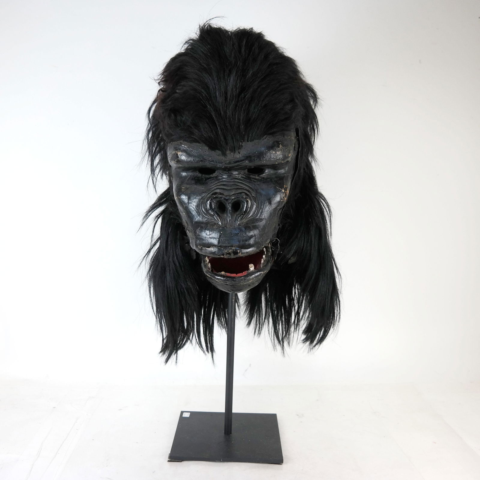 Papier Mache Gorilla Mask: Wearable gorilla mask with long hair, with zipper in back, on a stand. [Mask: 16" H x 9" W x 12" D; With hair: 22" H; On stand: 27" H].