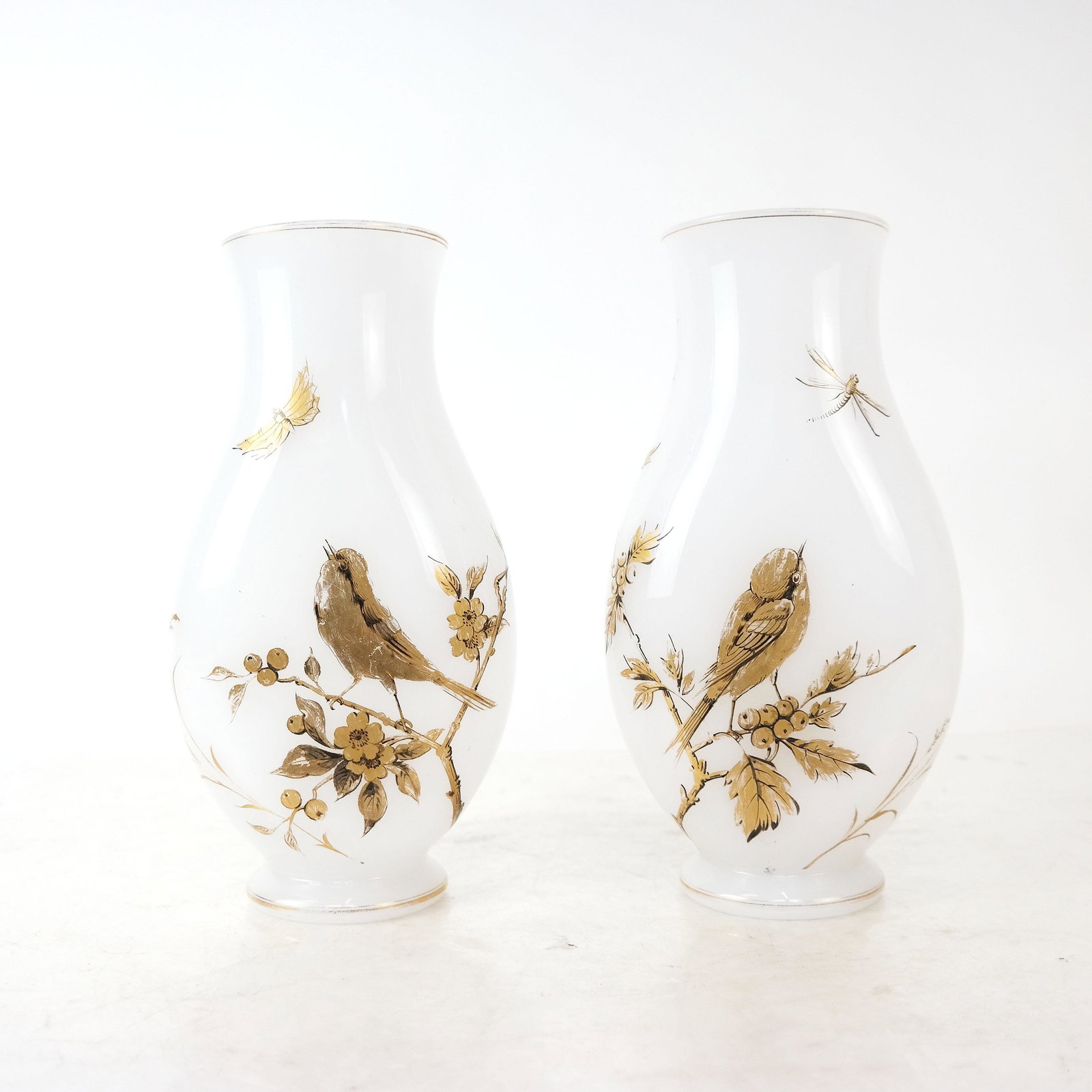 Pair of Antique French Opaline Glass Vases: Pair of opaline glass vases with gold painted songbird, berry and insect decoration. [10 3/8" H x 5 1/2" W x 3 1/2" D]. Some wear with loss to gold details.