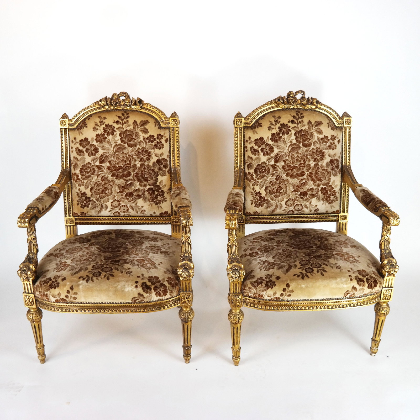 Pair of Carved Gilt Wood Fauteuils: Pair of floral velvet upholstered Louis XVI-style carved and gilt open arm chairs, circa 1940s. [41" H x 27" W x 21" D]. Cracks and gilt wear as with age and use.