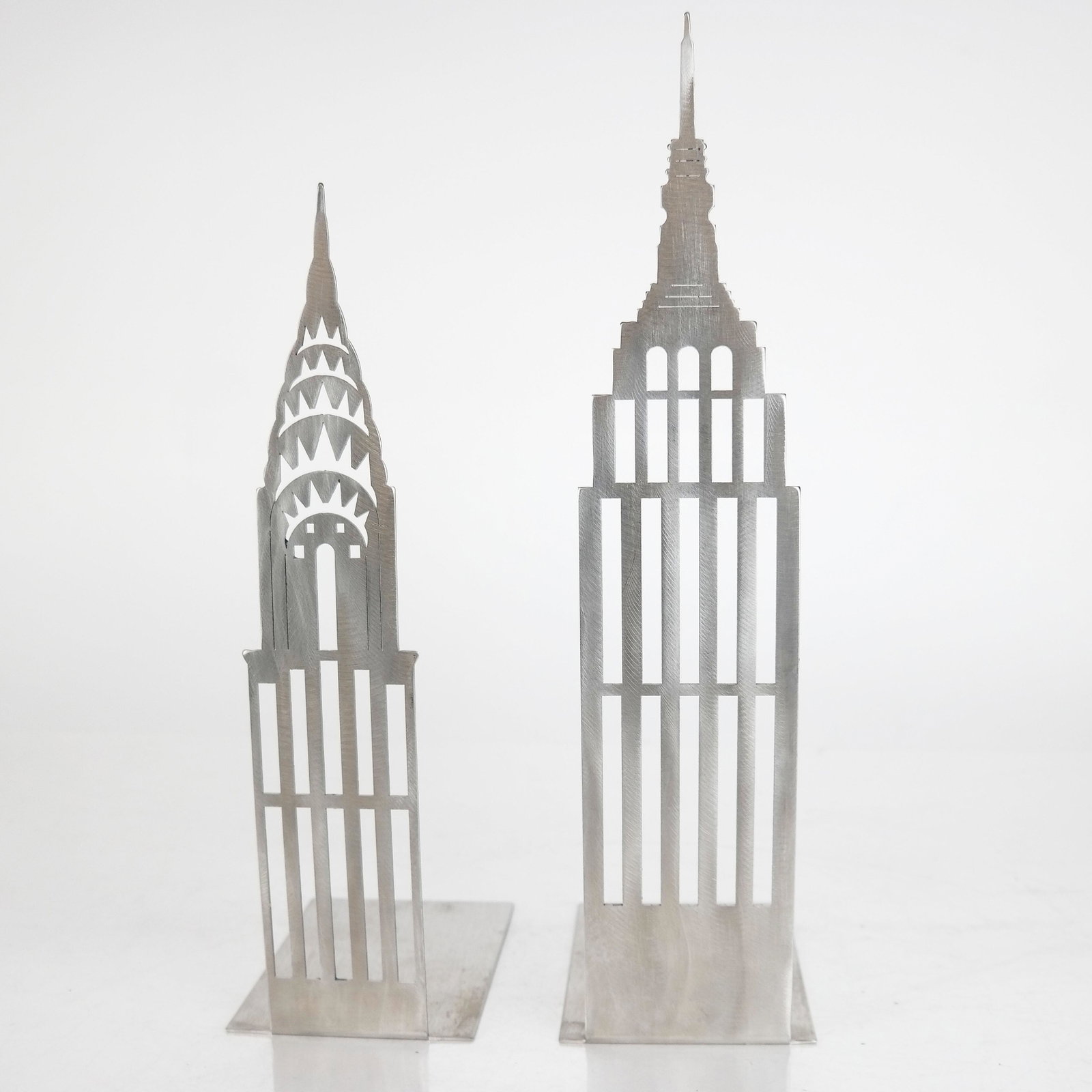 Pair Skyscaper Steel Bookends: Pair of steel skyscraper bookends of Empire State and Chrysler buildings. [Largest: 13" H]. In good condition.