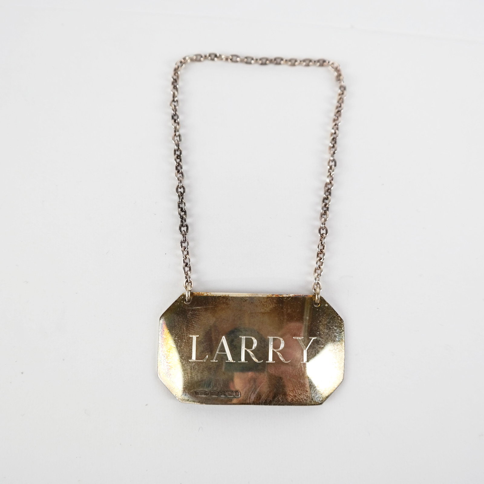 Sterling Silver Decanter / Bottle Tag: Sterling silver decanter / bottle tag on chain, reading "Larry". .63 ozt. [1 1/4" x 2"]. In good condition.