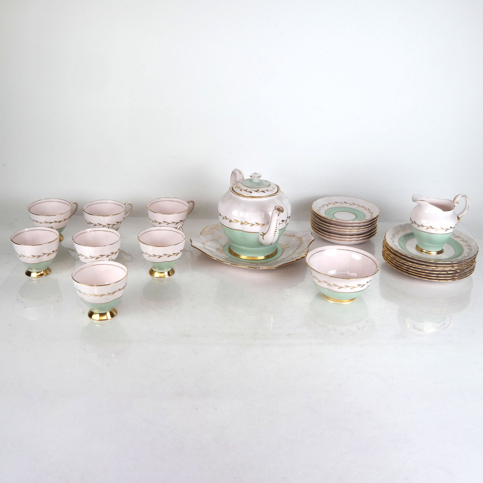 27-Pc. English Bone China Dessert Set: Dessert set comprised of teapot, cream, sugar bowl, waste bowl, plate, 6 cups, 8 saucers, and 8 plates, in pink and green with gilt trim. In good condition.