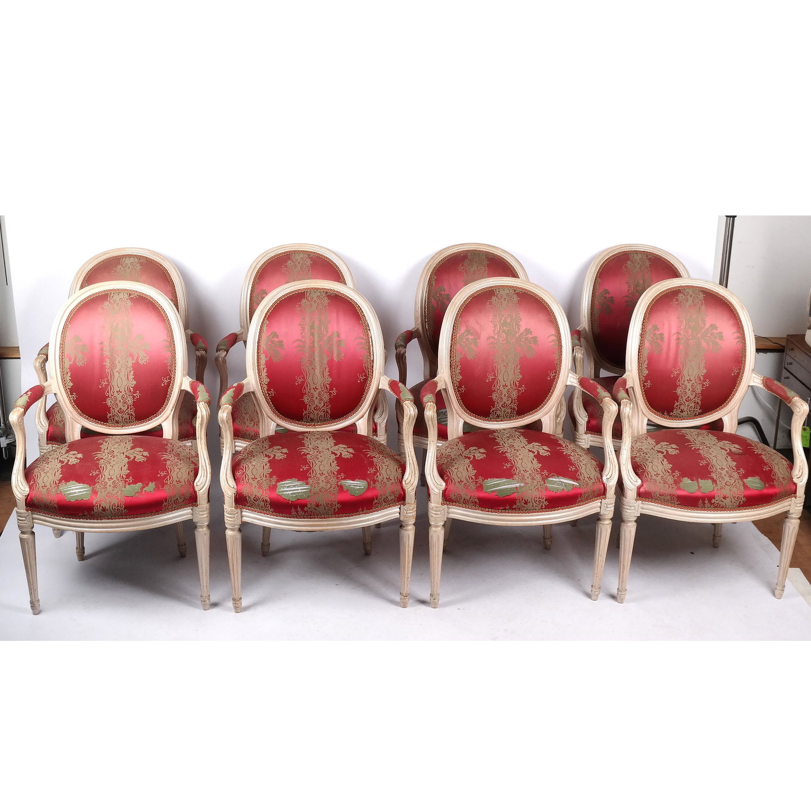 Set of 8 Louis XVI-Style Dining Chairs: Set of 8 painted and upholstered armchairs, with round backs and sloping upholstered arms, on fluted legs. Wear to upholstery. [37" H x 24" W x 25" D]. Wear to upholstery.