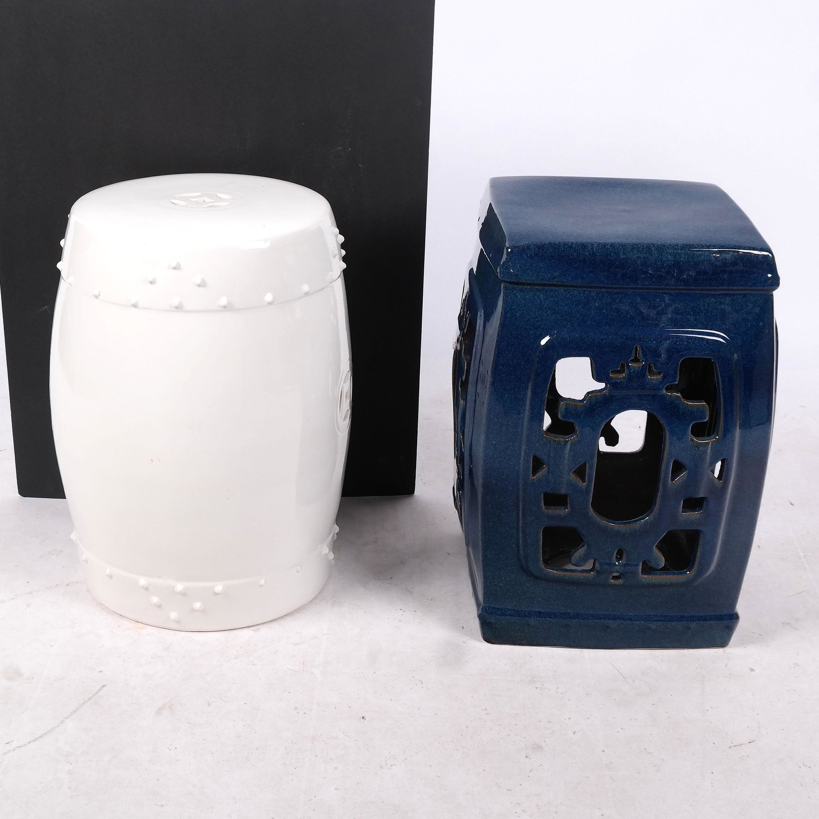 Two Chinese Porcelain Garden Seats: Two 20th century Chinese garden seats, one dark blue with cut-out sides, the other white, barrel-shaped. [19" H x 13" W x 13" D]. Both in good condition.