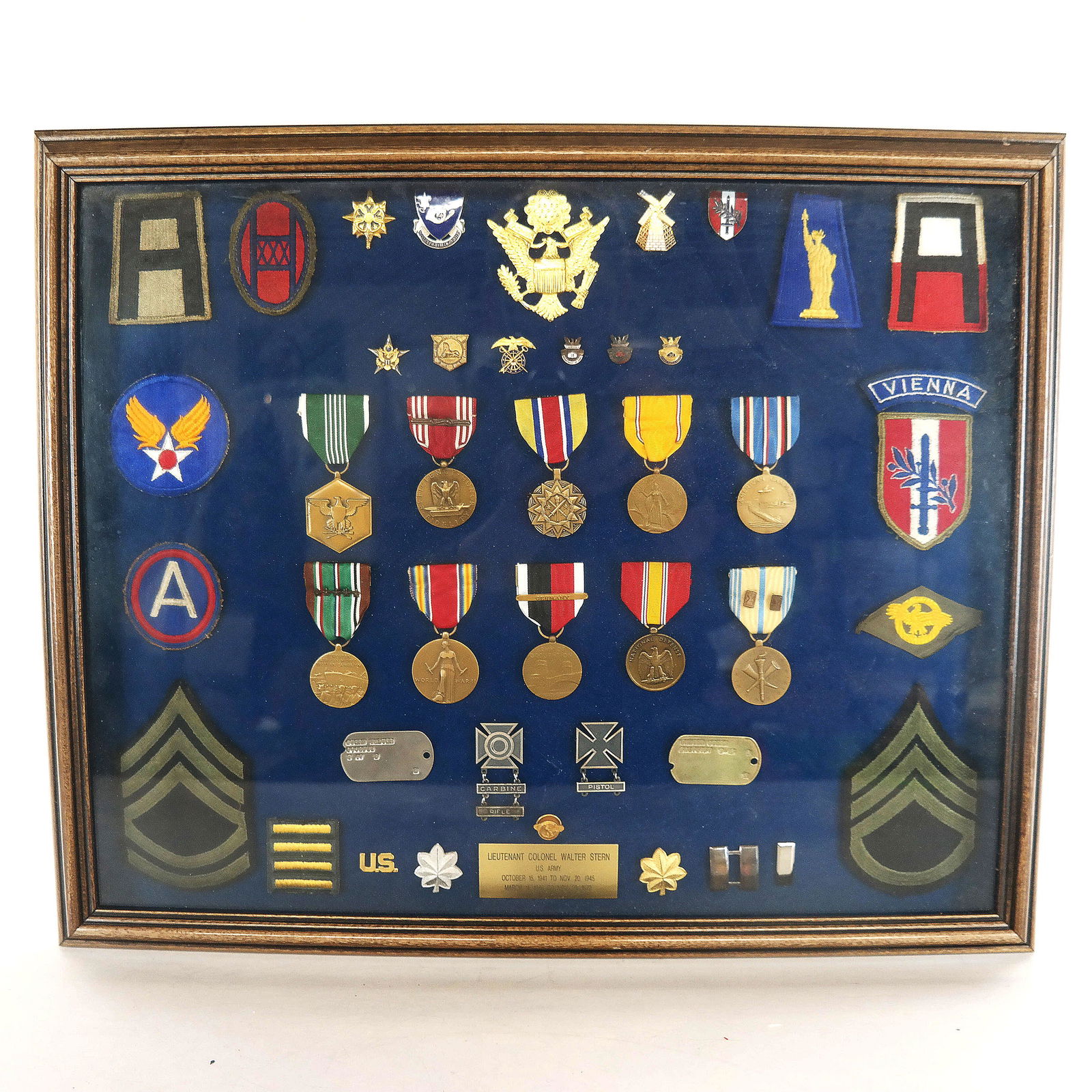 Collection of WWII Medals, Ribbons, Dog Tags, Etc.: Collection of WWII U.S. Army medals, pins, ribbons dog tags and patches, belonging to LTC Walter Stern, nicely displayed in a shadow box frame with a brass plaque. [Frame: 18" H x 22" W x 1 1/2" D]. I