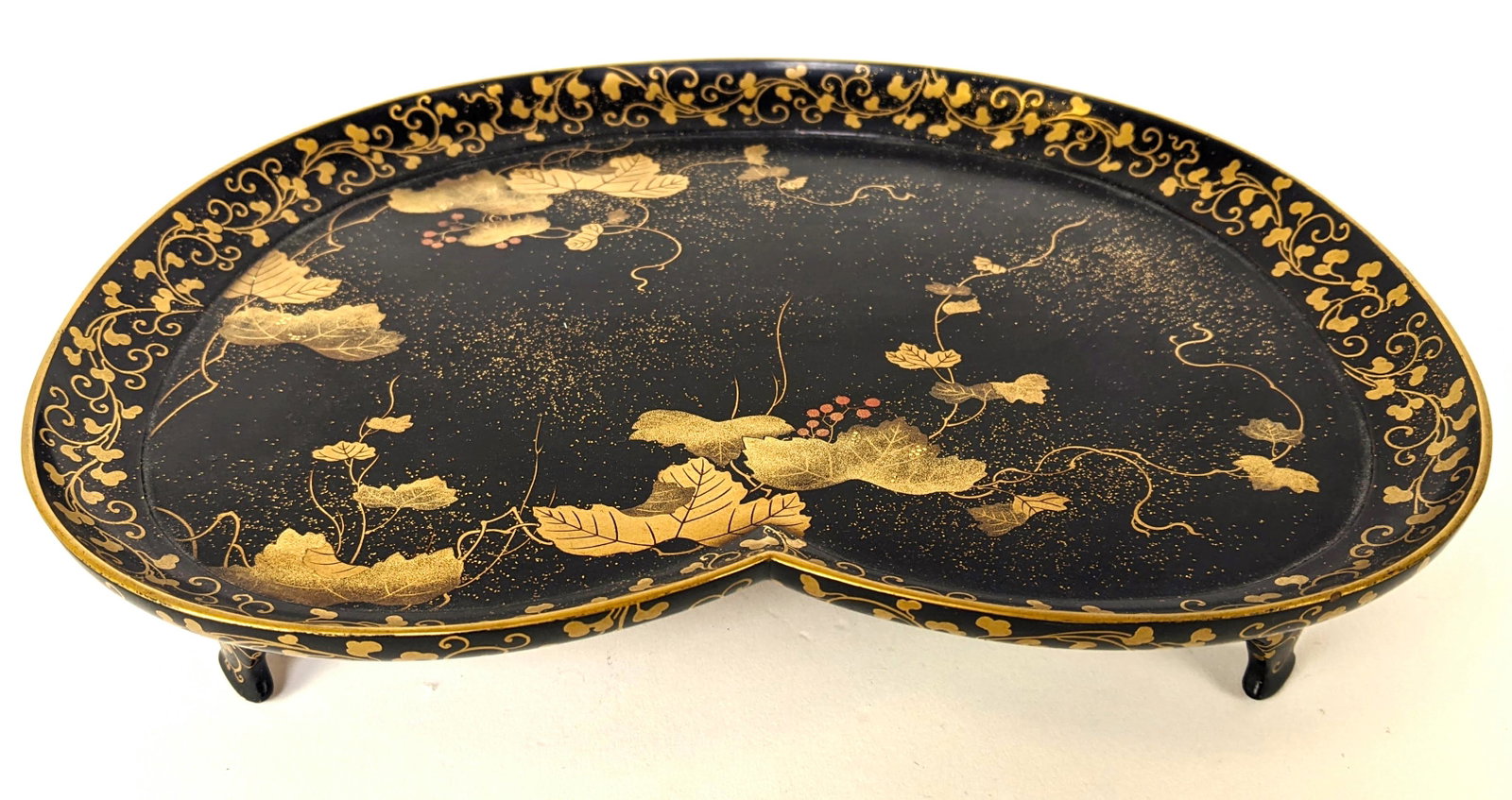 Japanese Lacquered Nishijin Footed Tray: Japanese black lacquered gilt floral decorated footed heart-shaped tray. From the Estate of June Hirsch Jones. [1 1/2" H x 8 1/2" W x 6 3/4" D]. In good condition.