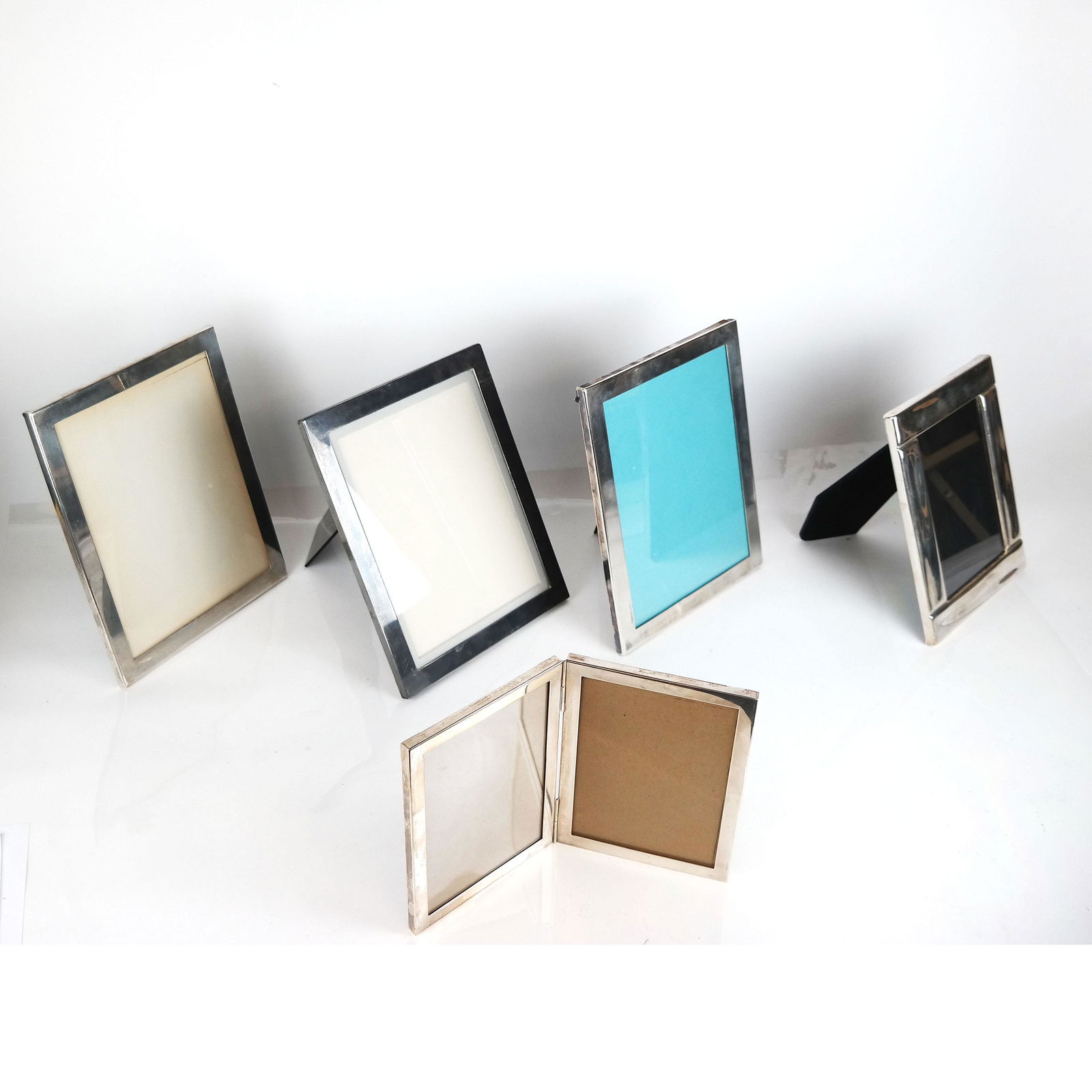 Five Tiffany Sterling Silver Picture Frames: One foldout double picture frame and four others, all sterling silver. Provenance: Estate of Florence & Herbert Irving. [Largest: 10 1/2" H x 8 1/2" W]. In good condition.