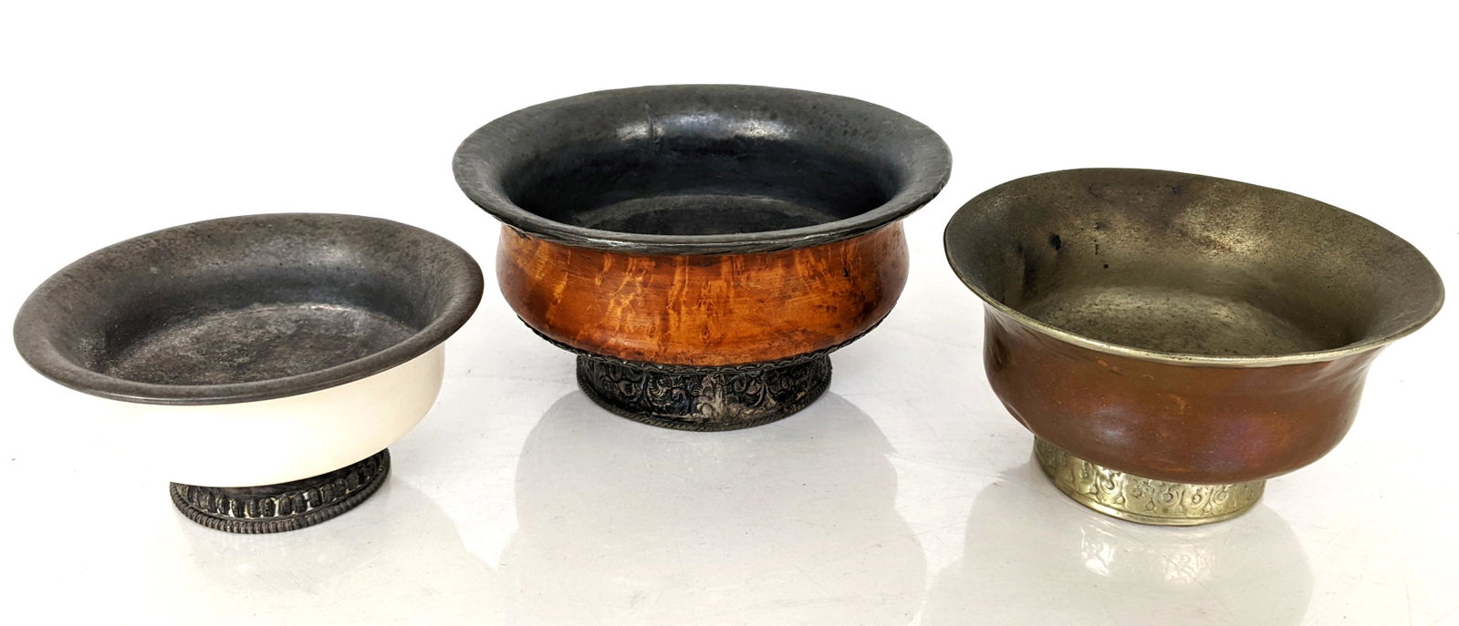 Three Tibetan Butter Bowls: Brass, Bone, etc.: Three Tibetan ring footed butter bowls, of brass, bone, wood and silver. From the Estate of June Hirsch Jones. [Largest: 2 1/2" H x 4 3/4" Diam.]. In worn condition.