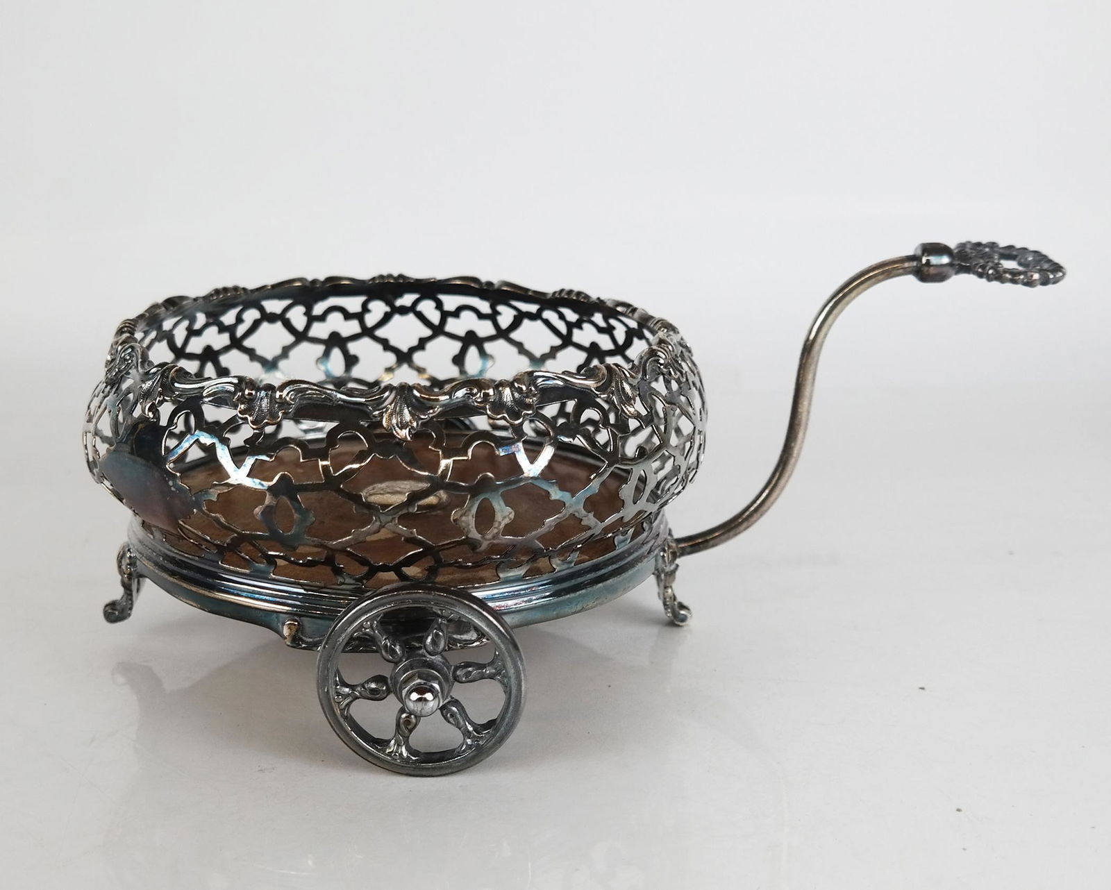 English Silver Plate Wine Trolley: English silver plate round wine coaster on two wheels with handles. [5" H x 9" W x 12" D]. In good condition.