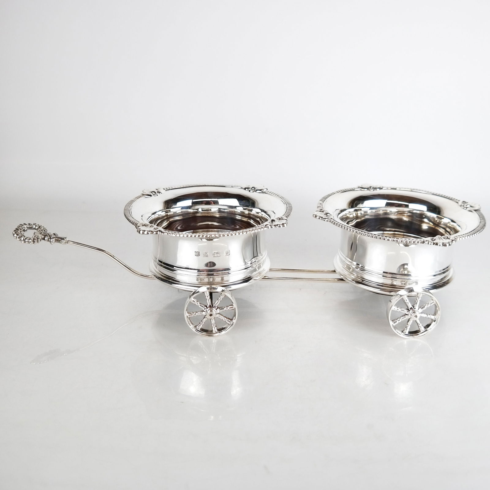 English Silver Bottle Trolley: English sterling silver wine bottle trolley. 44 ozt. inclusive. [Holders: 4" H x 18 3/4" W x 7 1/4" Diam.].