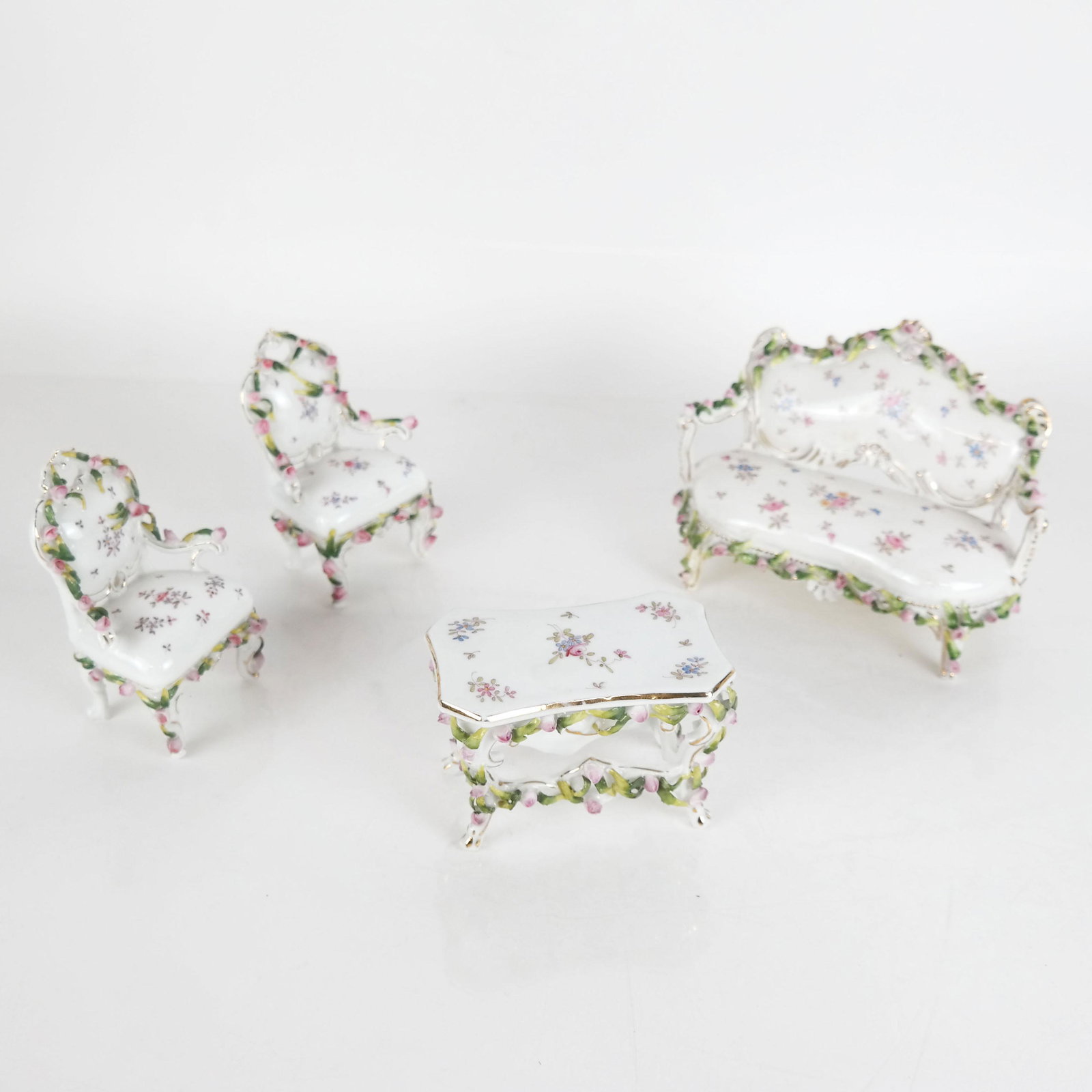 4-Piece Porcelain Salon Suite: Limoges-style porcelain settee, two chairs and a parlor table. [Settee: 4 1/2" H x 6" W x 3" D]. In good condition.