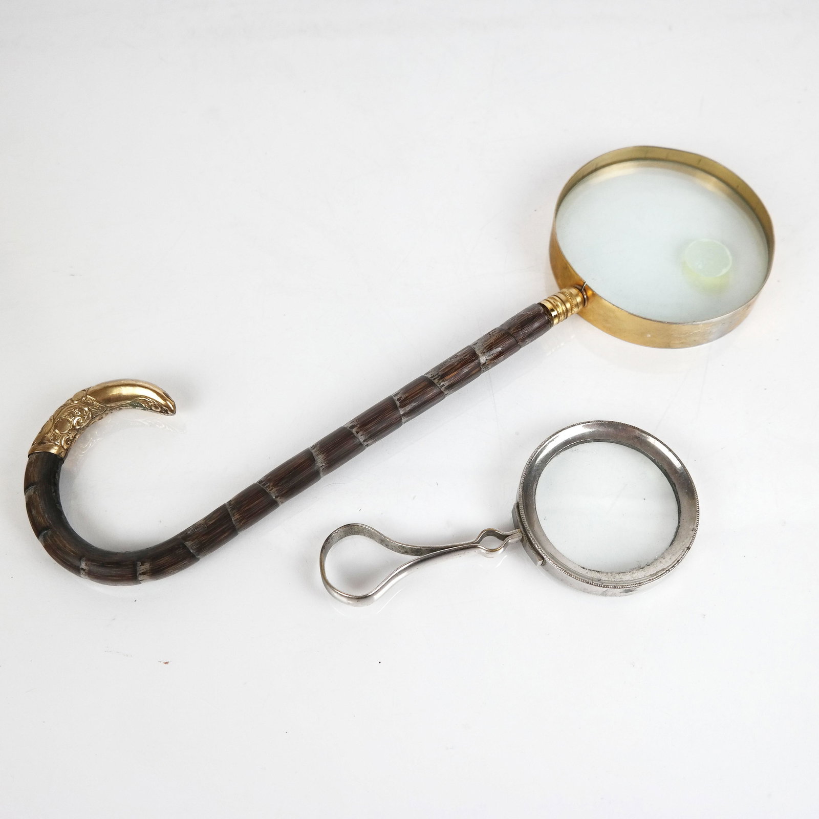 Two Magnifying Glasses: Two magnifying glasses, including one with plated loop handle [5" Long], and one with umbrella handle in faux bamboo [12" Long].