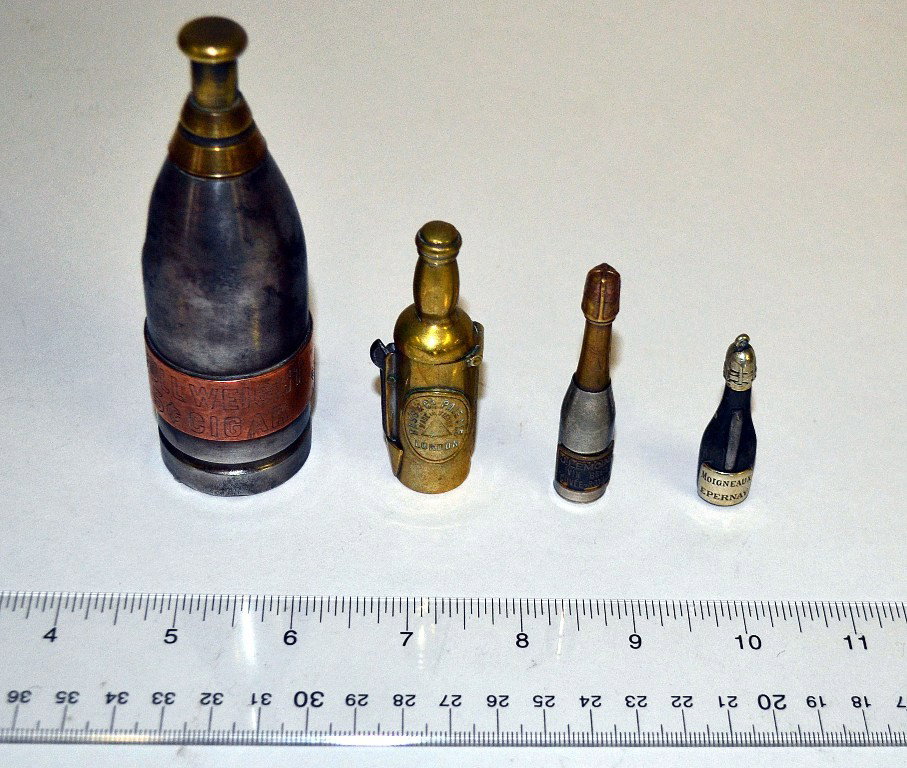 Tobacco: Four gadget bottles: Group Of Four Tobacco Theme Gadget Bottles. Composed of two cigar cutters, one cigar piercer, and a match safe. Dimensions variable from 1/2"Dia. x 2"H to 1-1/2"Dia. x 4-1/2"H.