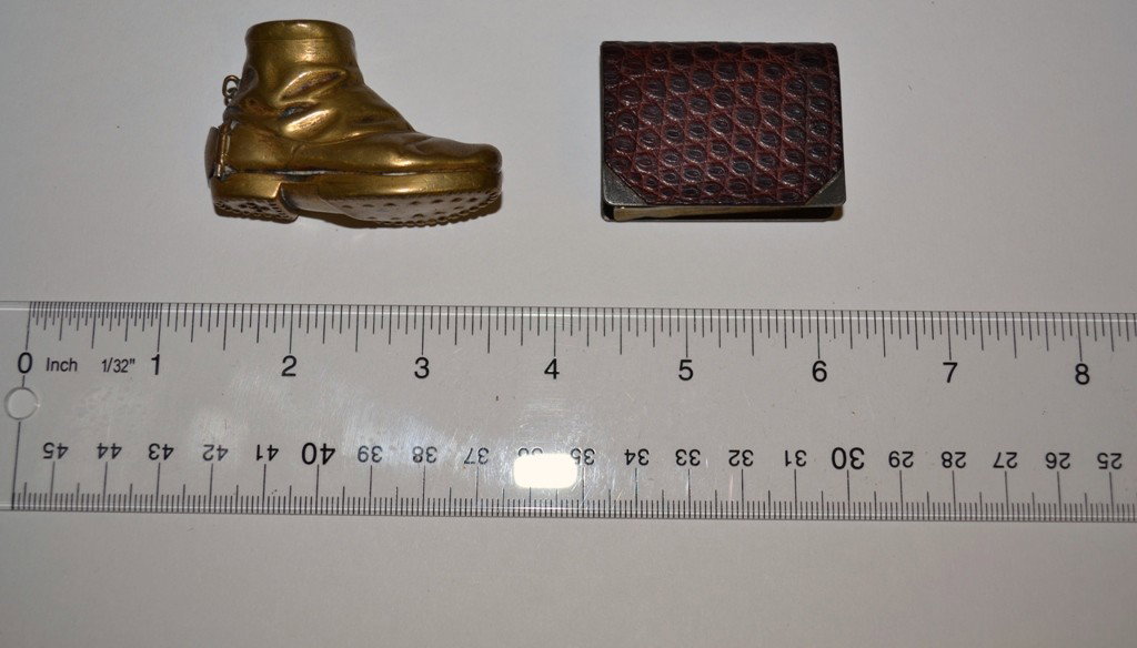 Tobacco: Two Miniature Mechanical Smoking Accessori: Two Miniature Mechanical Smoking Accessories. Comprises a brass boot form match safe and a leather bound book form lighter. Match Safe 2-1/4"W x 1"D x 1-3/4"H. Lighter 1-3/8"W x 1/2"D x 1-3/4"H.