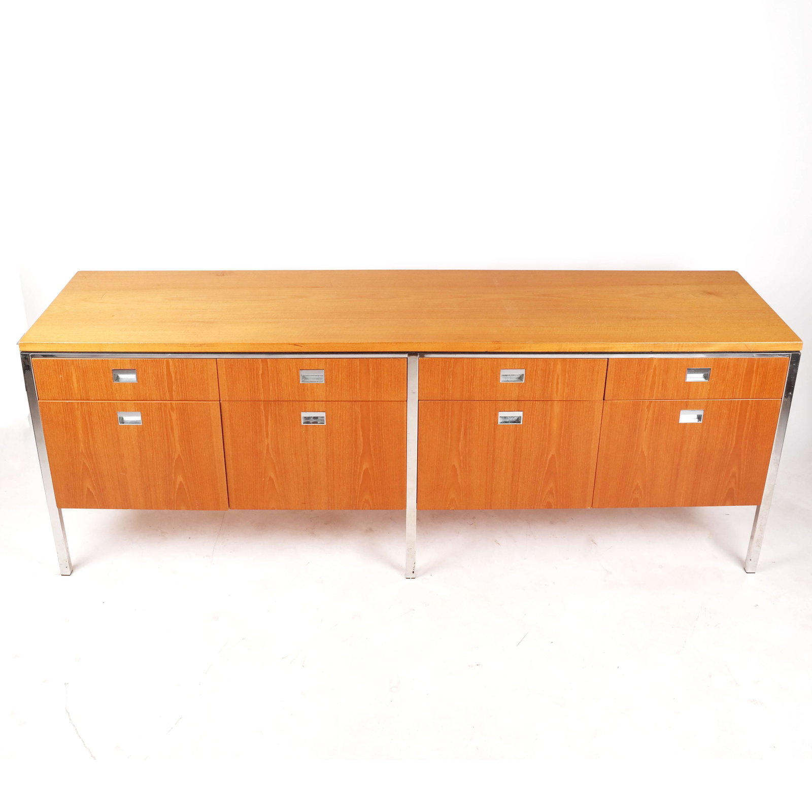 Gordon Bun Shaft Credenza: Mid-century modern birch and chrome credenza with 8 drawers. [26 1/2" H x 72" W x 19" D]. Wood finish in good condition. With wear and pitting to chrome.
