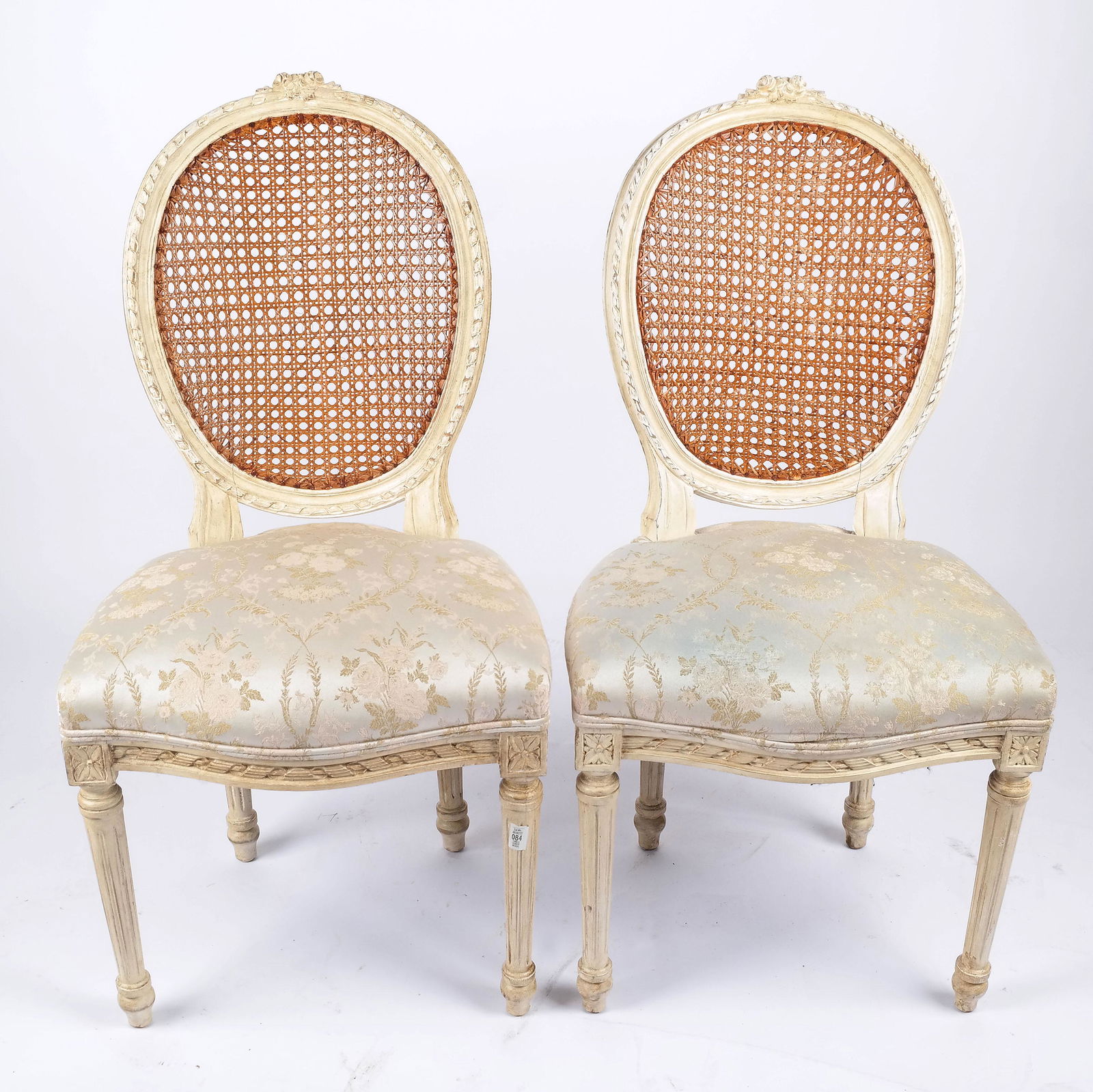 Pair of Louis XVI-Style Caned Side Chairs: Pair of Louis XVI-style caned and upholstered side chairs with floral upholstered seats. [38" H x 19 1/2" W x 22" D]. Wear to decoration; soiling to fabric.