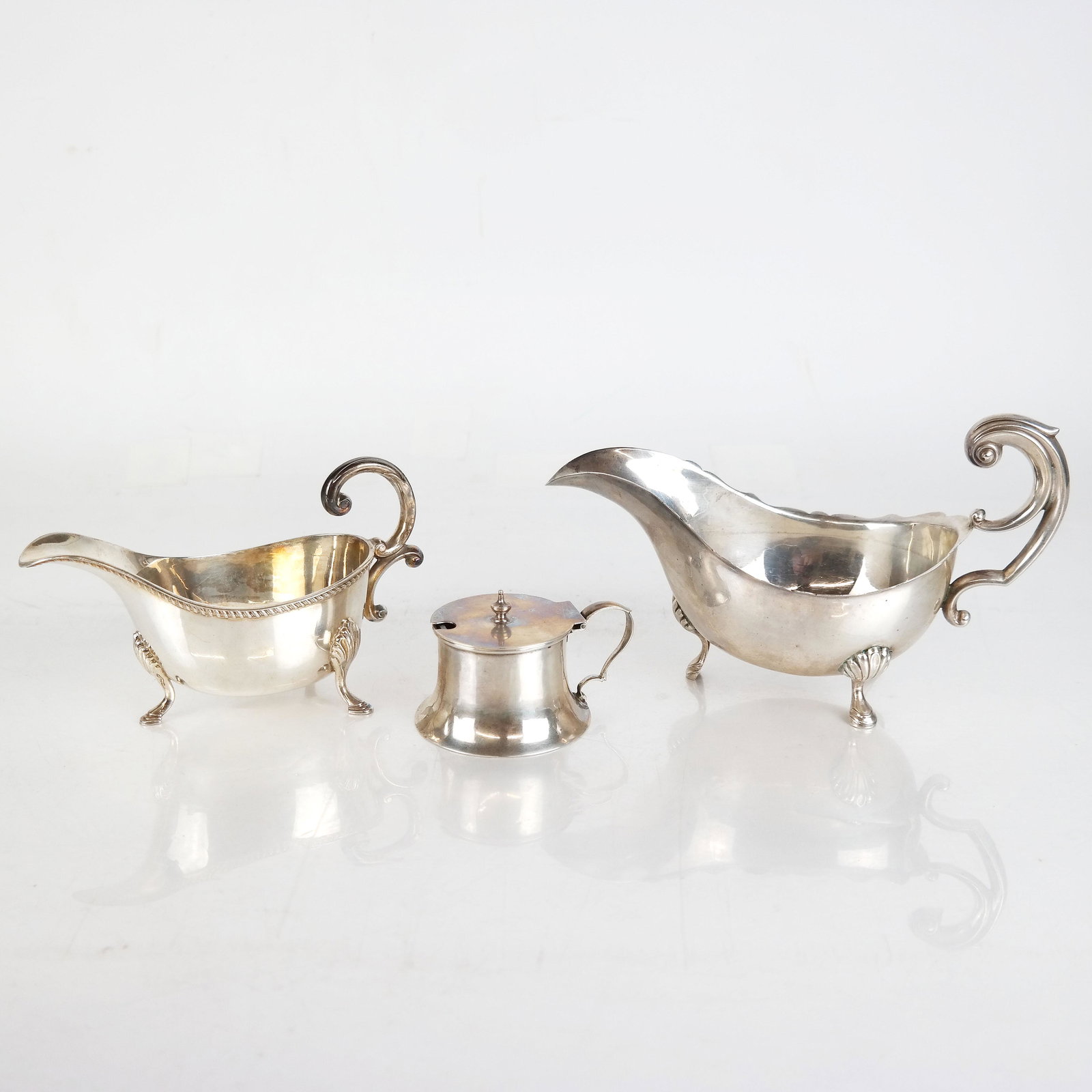 2 Silver Georgian-Style Gravy Boats & Salt Cellar: Two silver Georgian-style gravy boats together with a Gorham salt cellar with a cobalt blue glass liner. Marked to bases. 15.6 ozt. [Larger: 5" H x 8 1/4" W x 4" D].