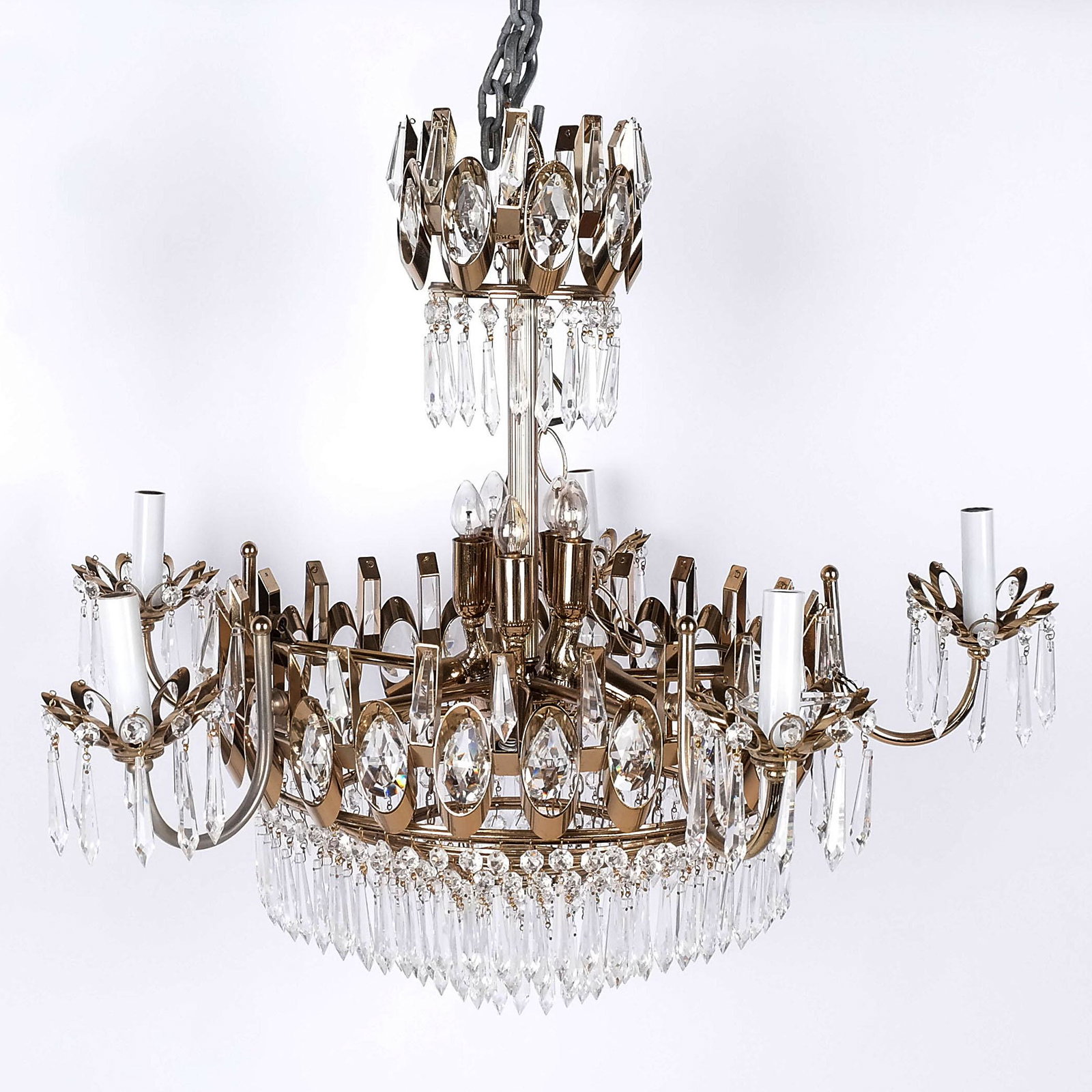 Mid-Century Retro 16-Light Chandelier: Mid-century retro 16-light chandelier in the neoclassical taste, with six arms around ten smaller lights and tiered pendant prisms. [27" H x 28" Diam.]. In overall good condition.