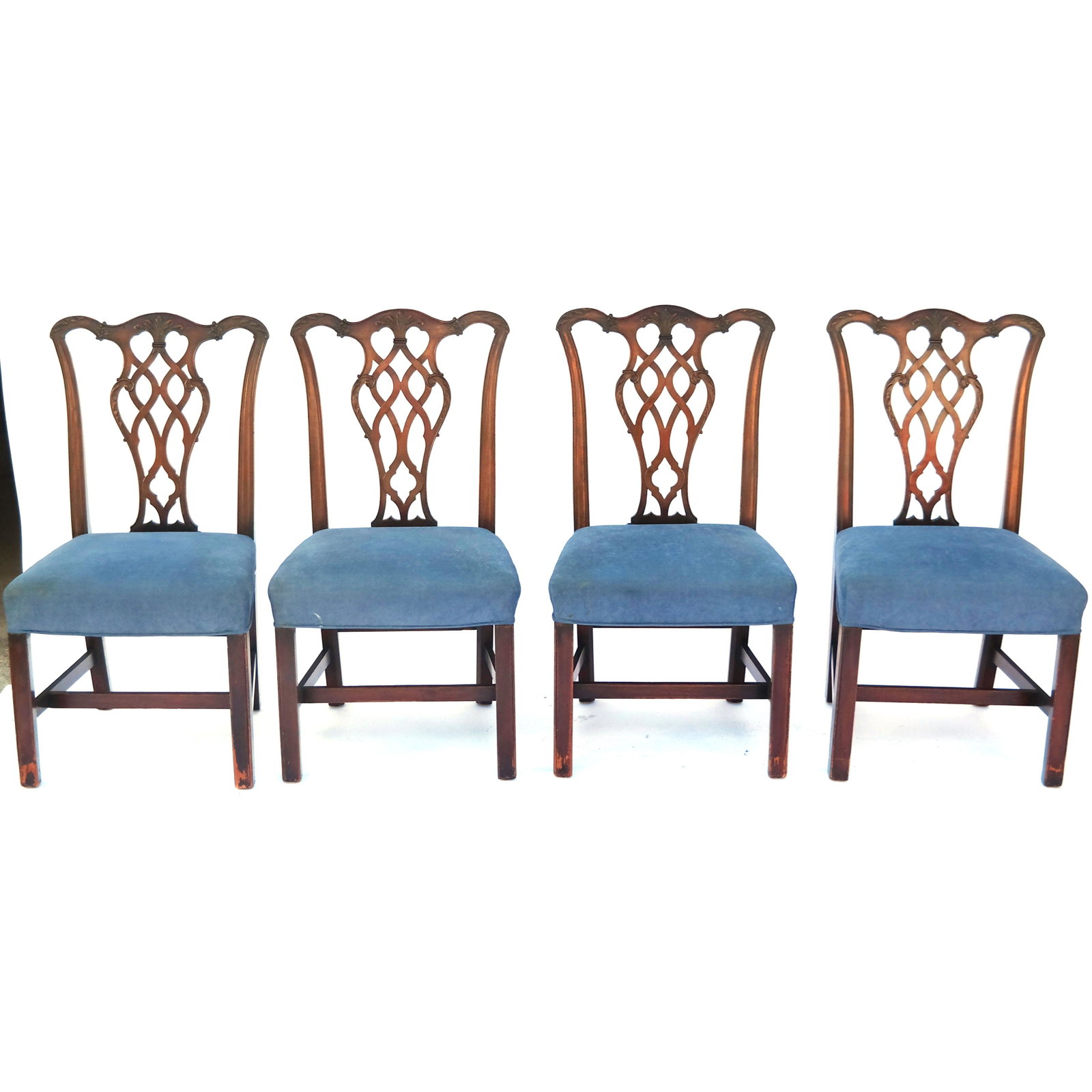 Four Carved Mahogany Dining Chairs: Four carved mahogany dining chairs in the Chippendale taste, with blue upholstered seats. [38" H x 20 1/2" W x 20" D]. Fading, scuffs, wear.