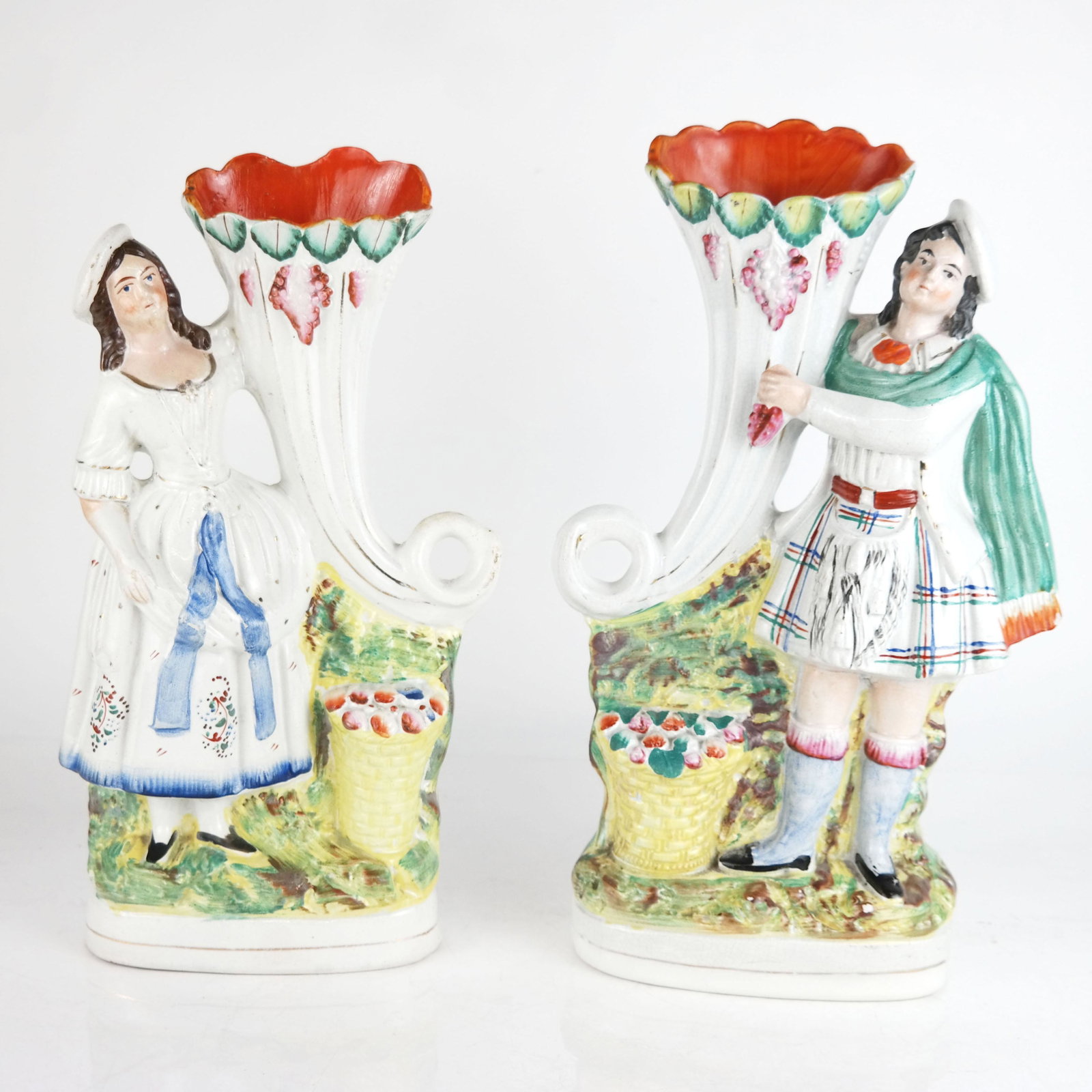 Pair of English Painted Porcelain Spill Vases: Pair of English painted porcelain spill vases, in the manner of Staffordshire, modeled as Scottish Highland couple with cornucopia, unmarked. [13 3/4" H x 8" W x 3 1/2" D]. Restoration to top edges, s